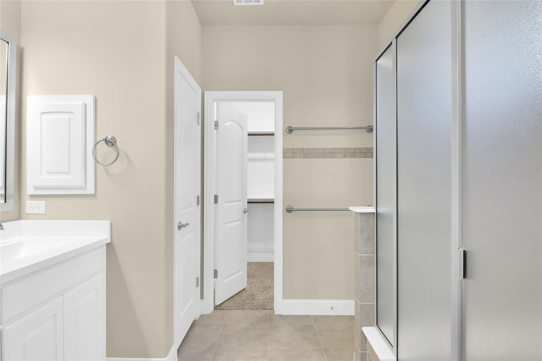 Full bath featuring vanity, a stall shower, and light tile patterned floors.