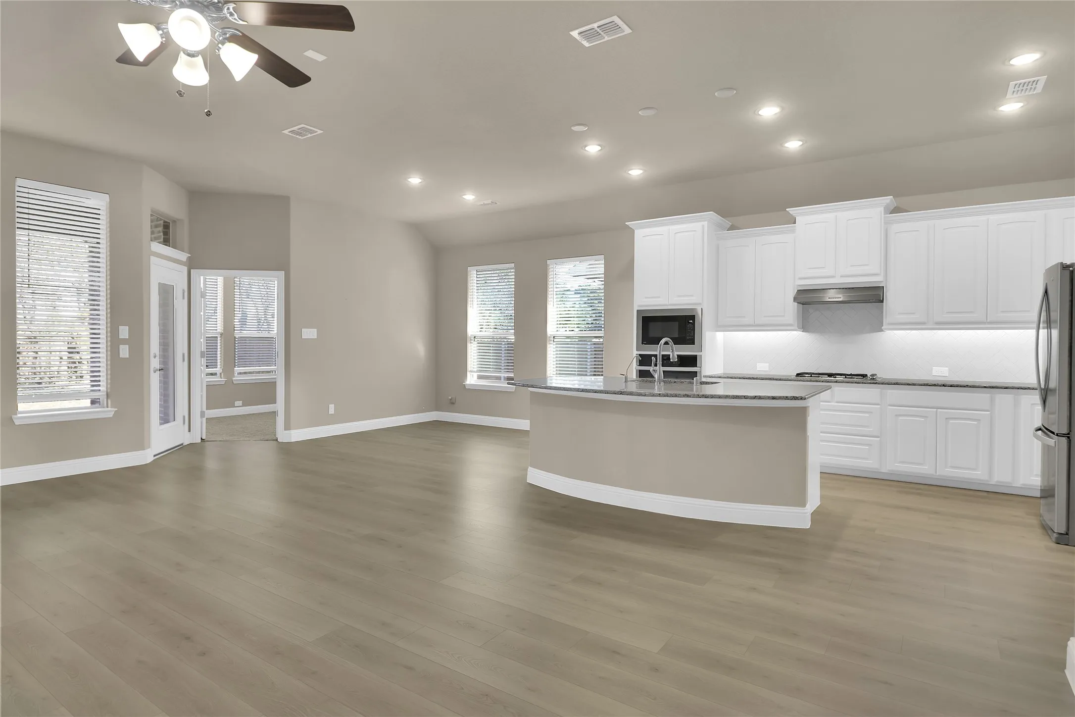 Kitchen featuring open floor plan, white cabinetry, recessed lighting, an island with sink, and appliances with stainless steel appliances.