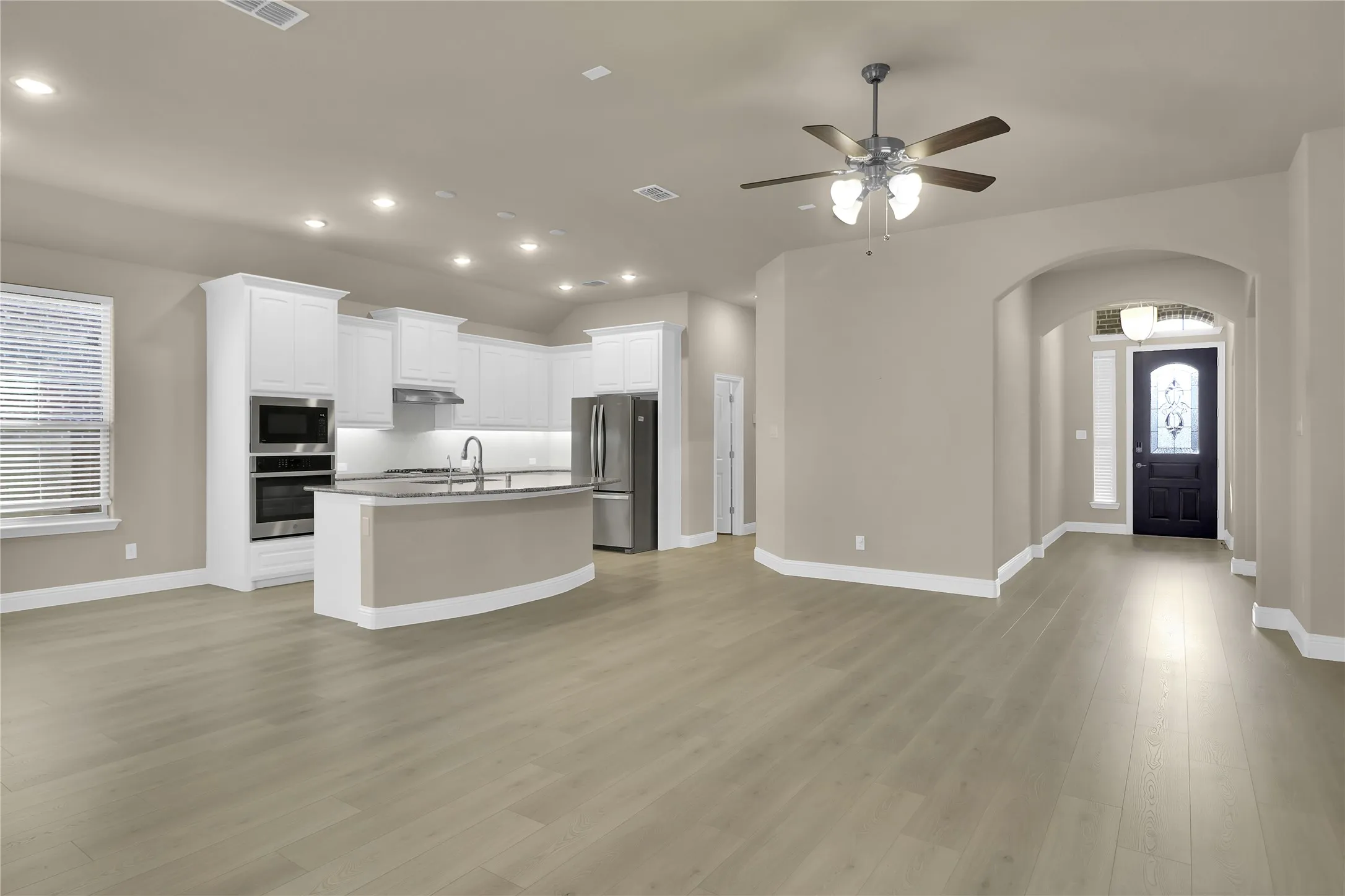 Kitchen with plenty of natural light, open floor plan, arched walkways, white cabinetry, and recessed lighting
