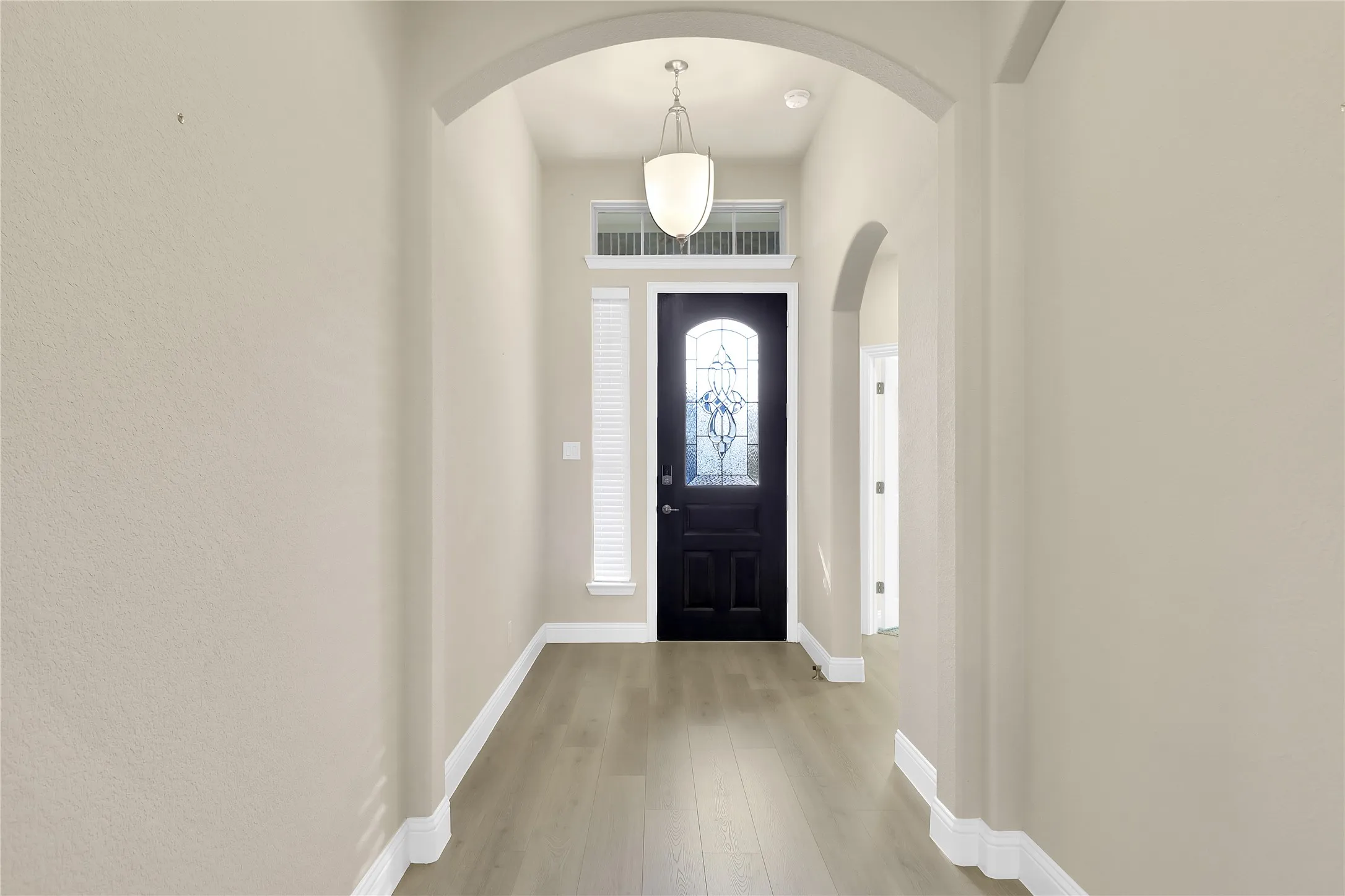 Foyer entrance featuring light wood-style floors and arched walkways