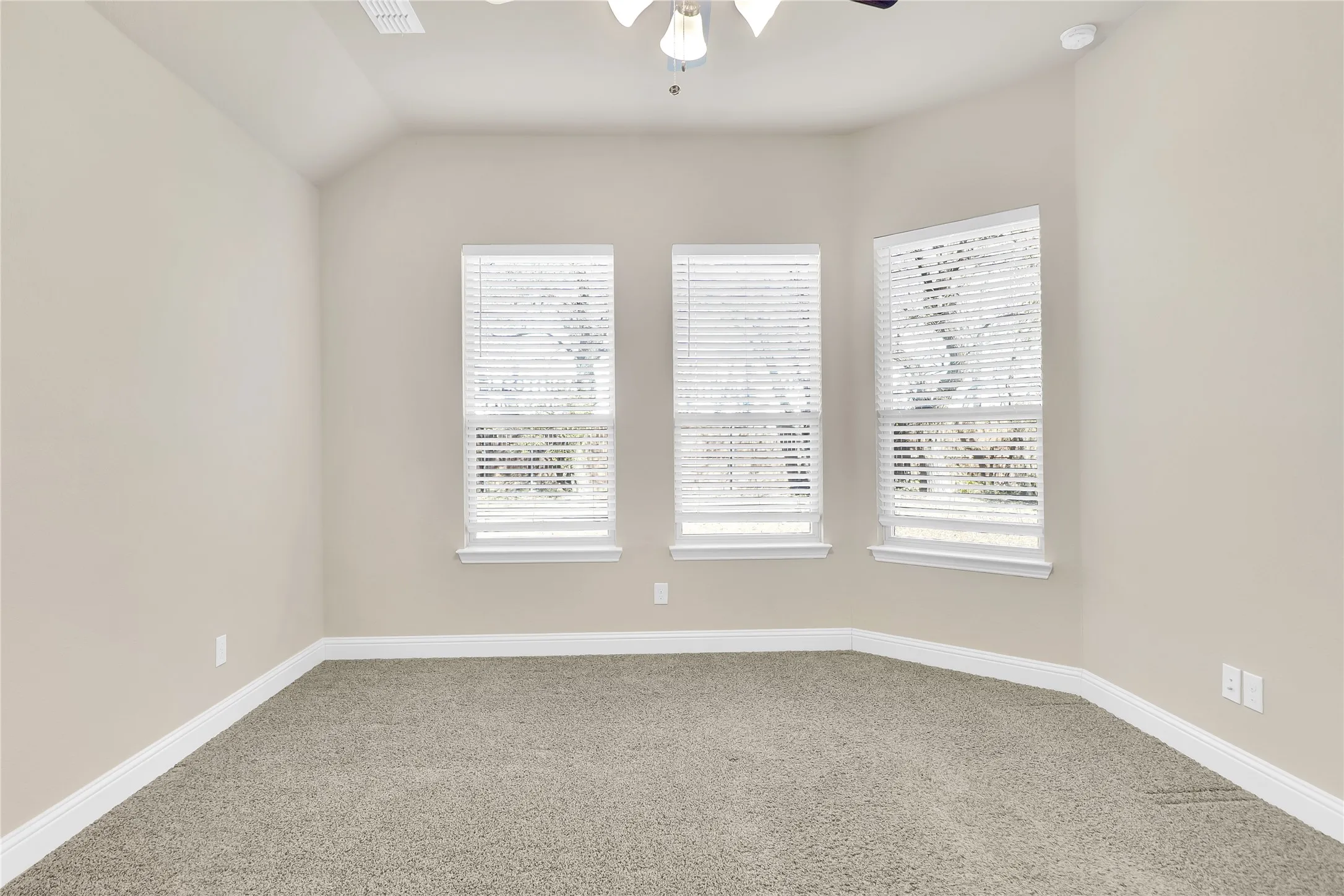 Spare room with a ceiling fan, light colored carpet, and lofted ceiling