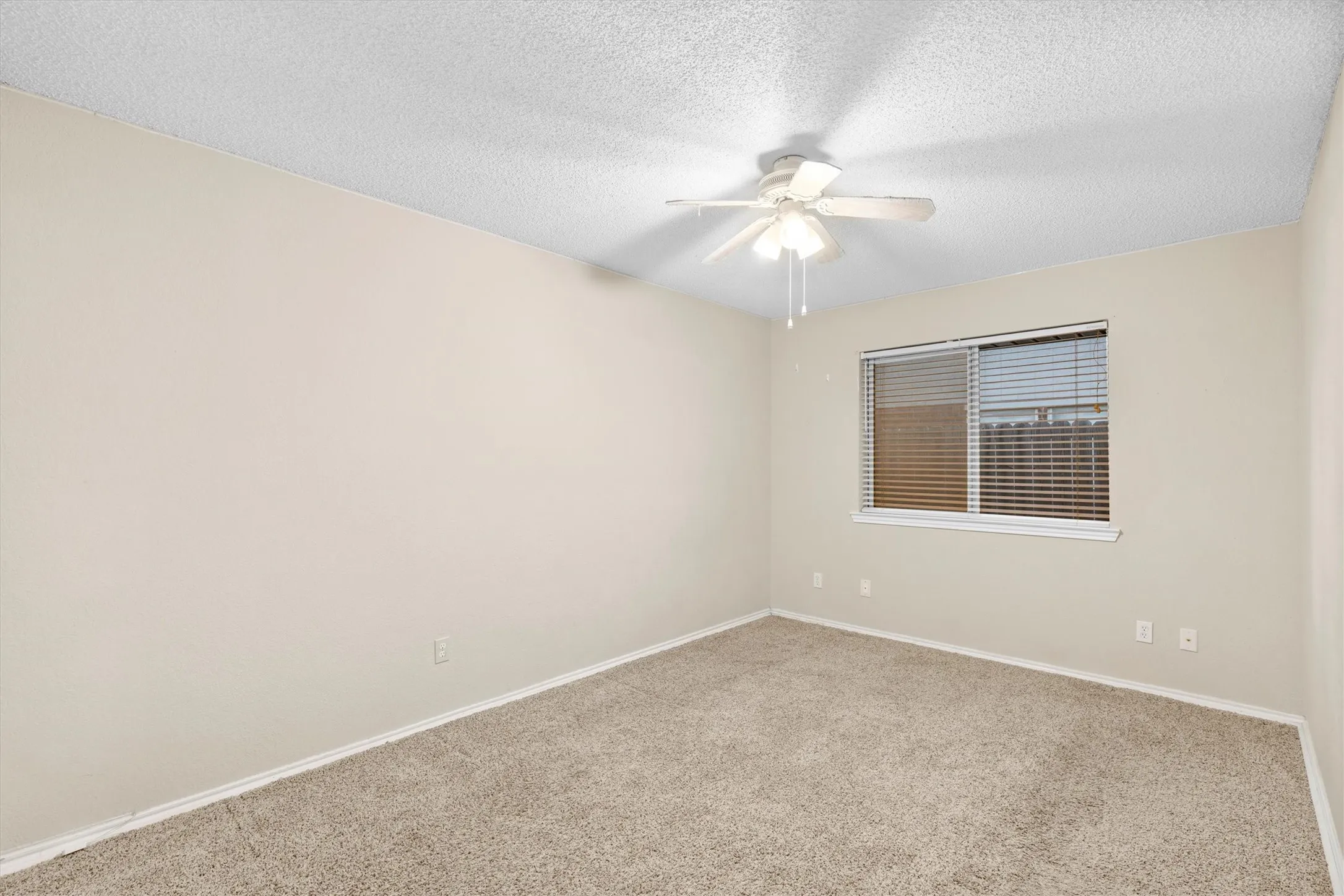 Spare room featuring a textured ceiling, carpet, and a ceiling fan