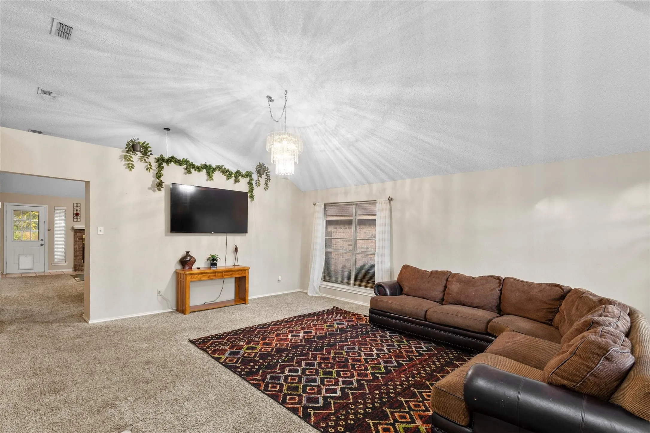 Carpeted living area featuring lofted ceiling and a chandelier