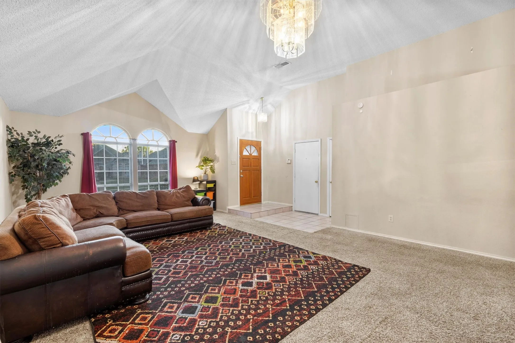 Living area featuring lofted ceiling, carpet, and a chandelier