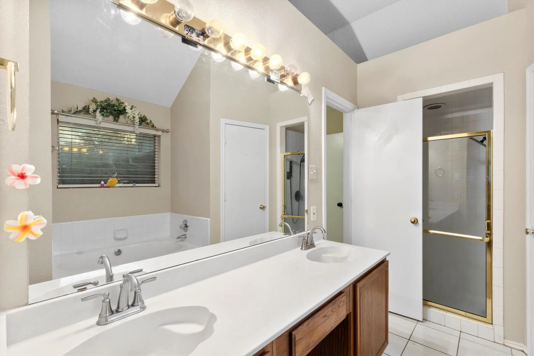 Bathroom with double vanity, a stall shower, light tile patterned floors, and a garden tub