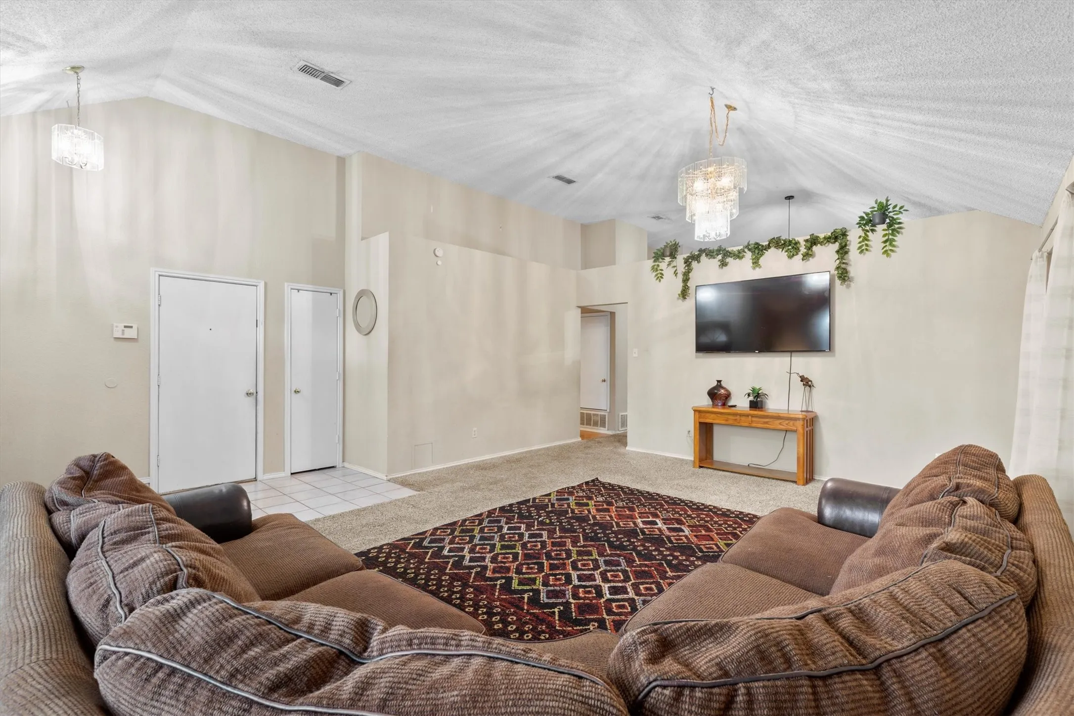Living area with vaulted ceiling, a chandelier, carpet floors, and a textured ceiling