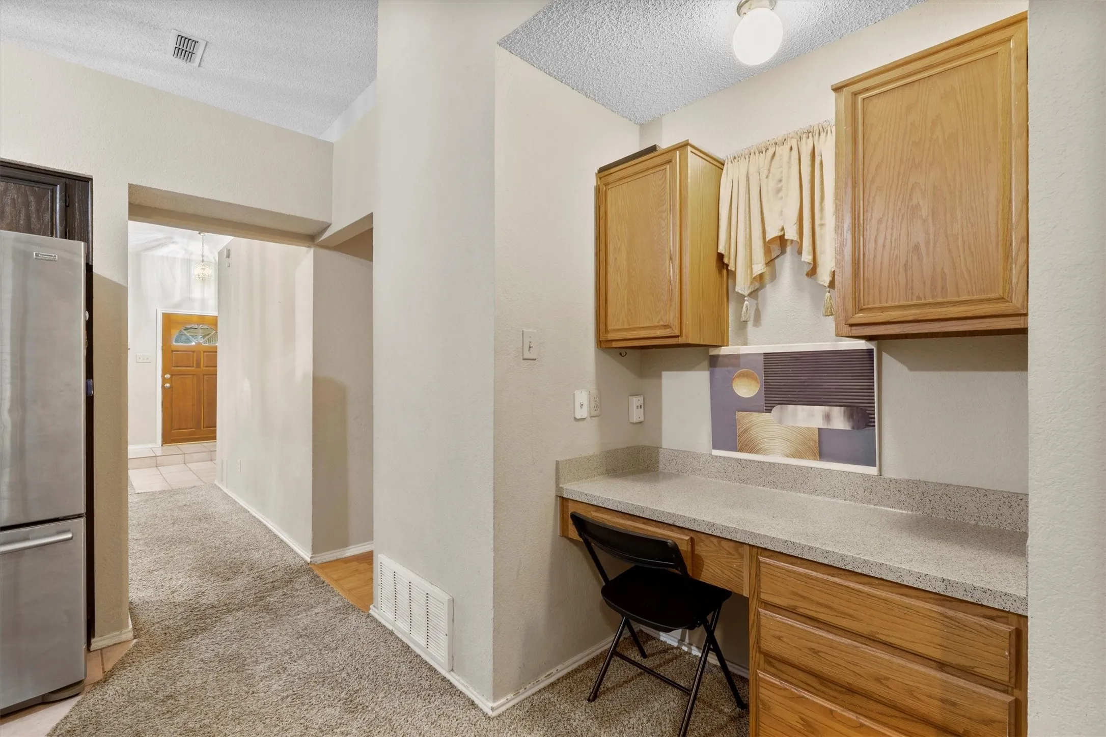 Office area with a textured ceiling, light carpet, and built in study area