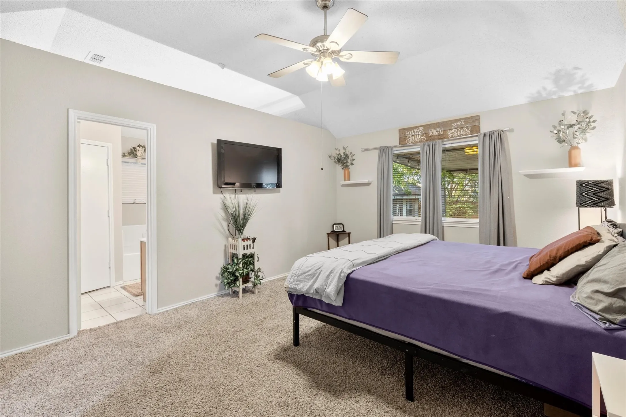 Bedroom featuring light colored carpet, vaulted ceiling, and ceiling fan