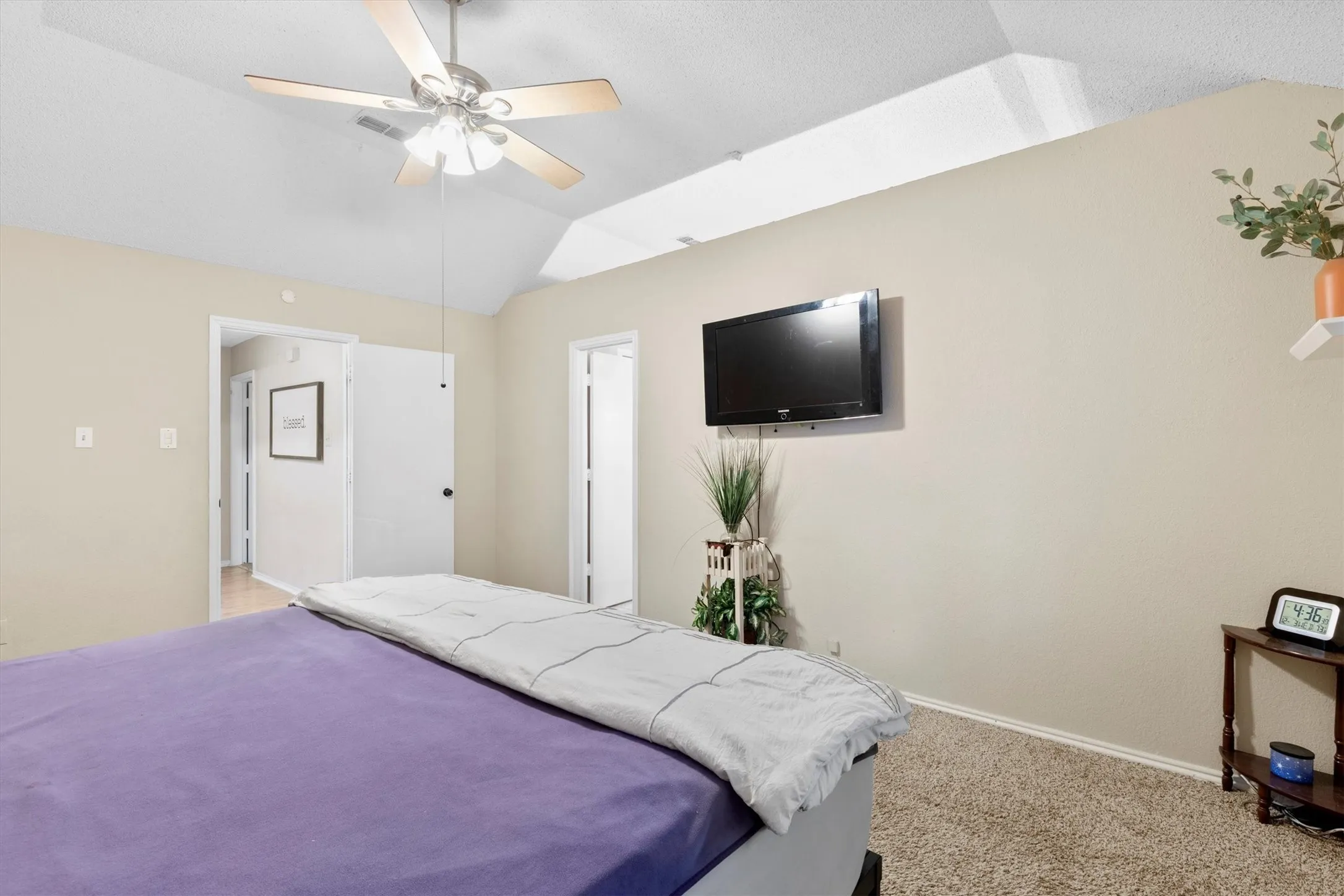 Bedroom featuring vaulted ceiling, light carpet, and a ceiling fan