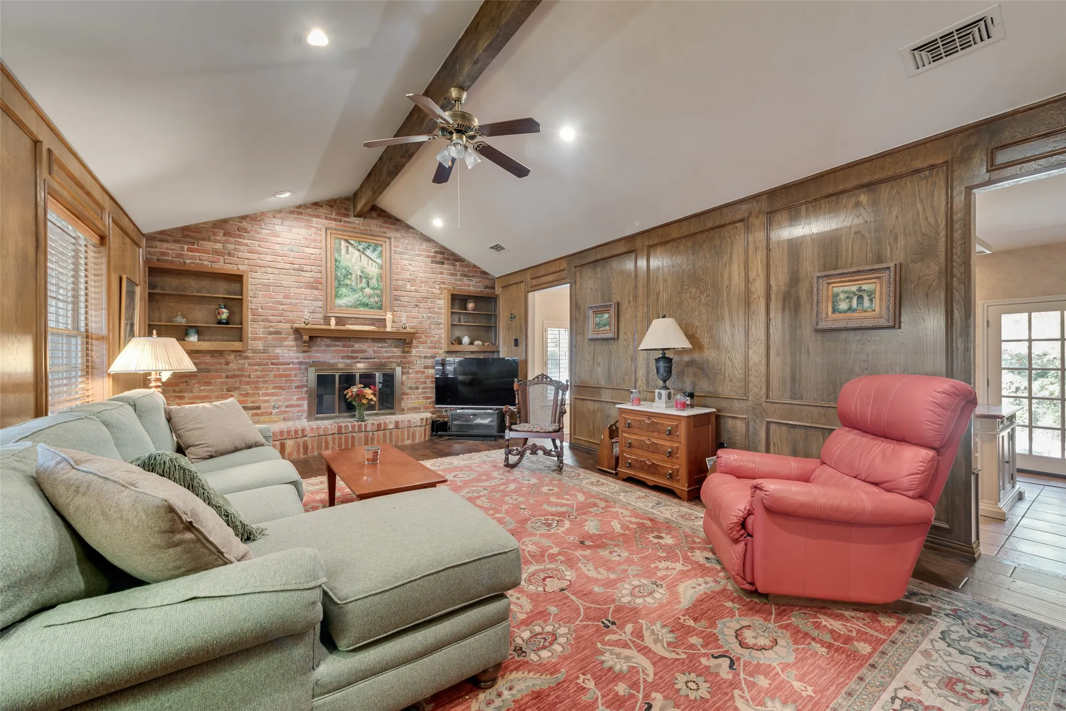 Cozy living room with large windows facing the front of the house and a comfy fireplace. These two openings lead to the dining room on the left and the kitchen on the right.