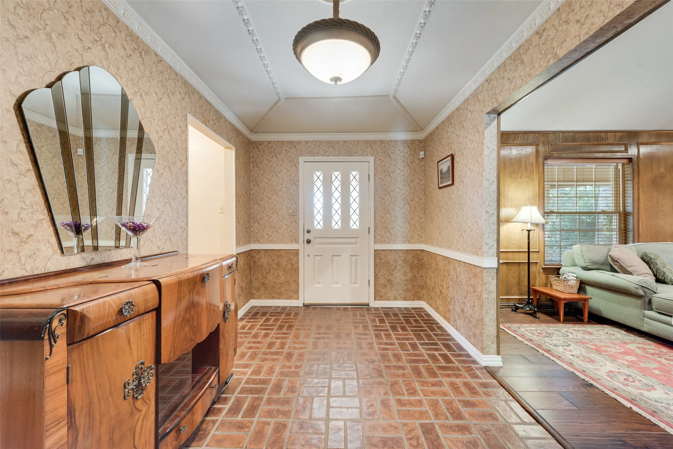 Elegant entryway with a vaulted ceiling and crown molding. Opens to the living room and a hallway to a downstairs bedroom