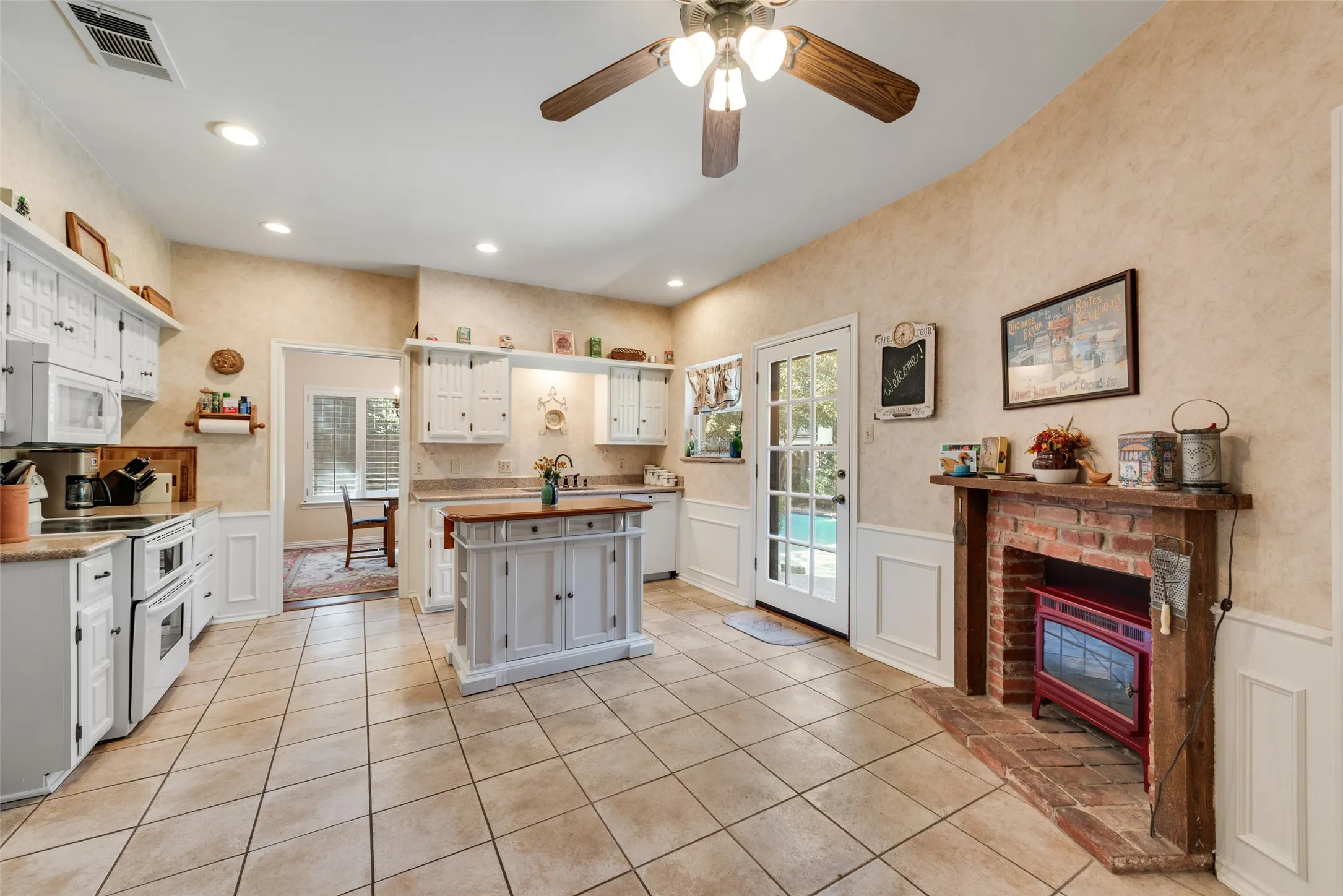Spacious kitchen with enough room for an eat-in kitchen. Also, access to the backyard and pool. The kitchen also features a cozy faux fireplace