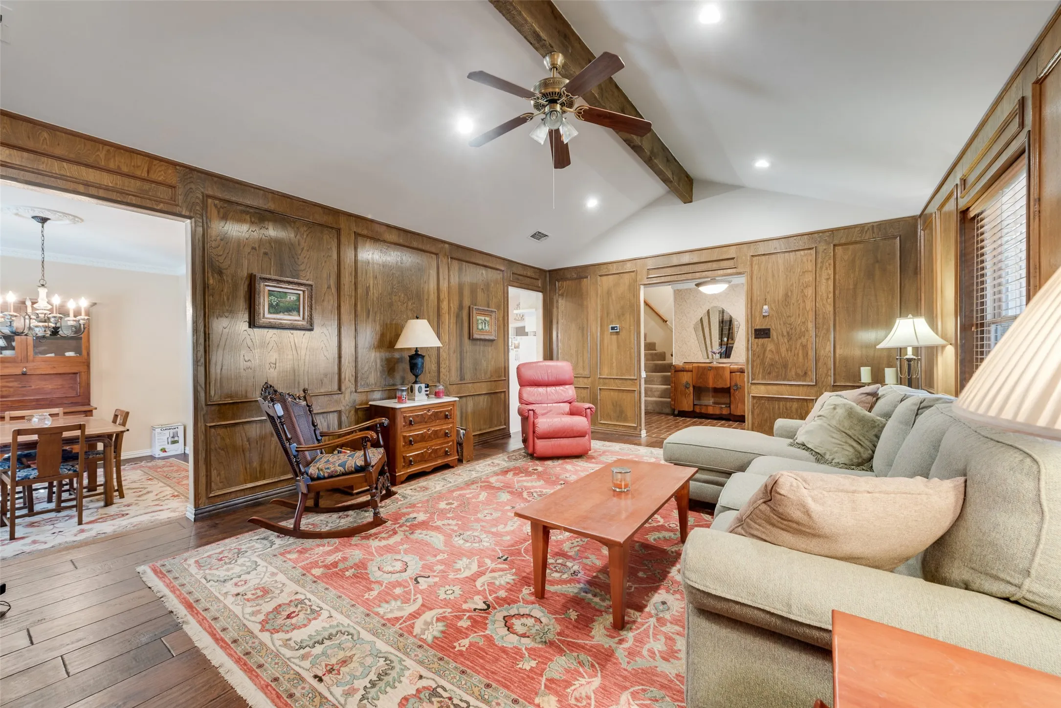 Cozy living room with large windows facing the front of the house and a comfy fireplace. These openings lead to the dining room on the left, kitchen in the middle, and entry way on the right.