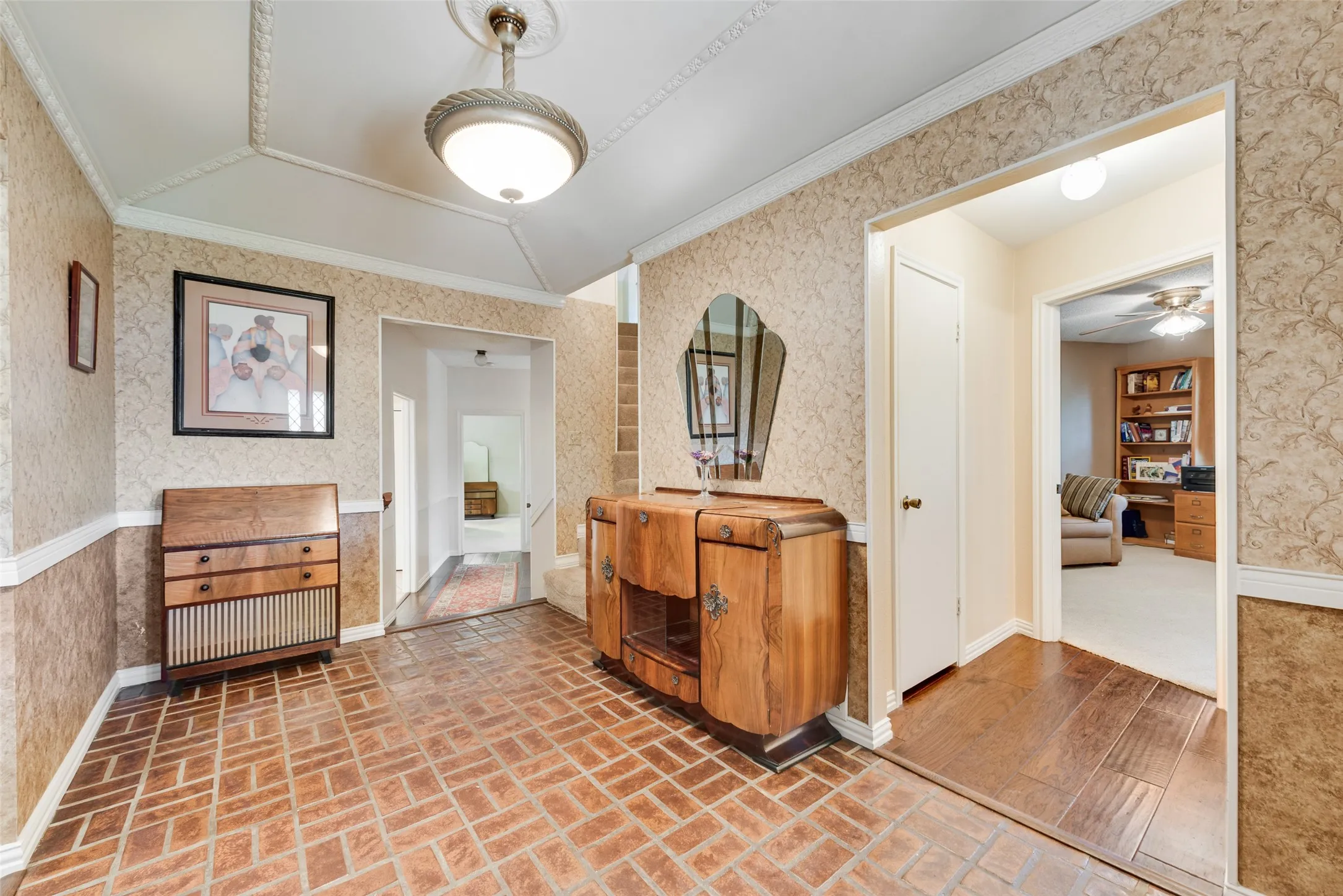 Vantage point as you enter the home. To the right is a downstairs bedroom and bathroom. Straight ahead is the stairwell to 2 upstairs bedrooms and a hallway leading to the kitchen on the left and primary bedroom straight ahead. To the left the entry opens to the living room.