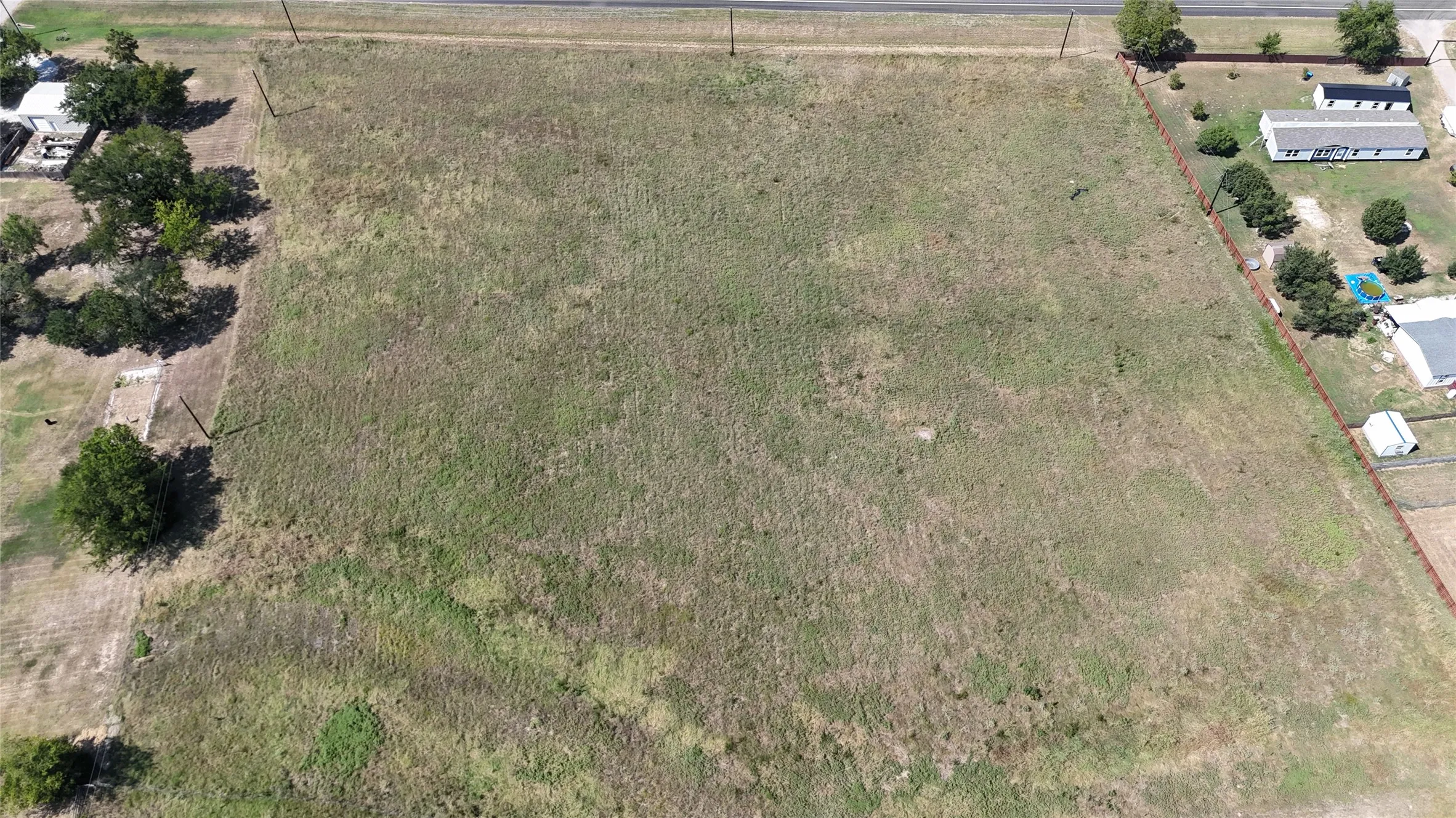 Expansive rectangular lot featuring natural grass and scattered trees