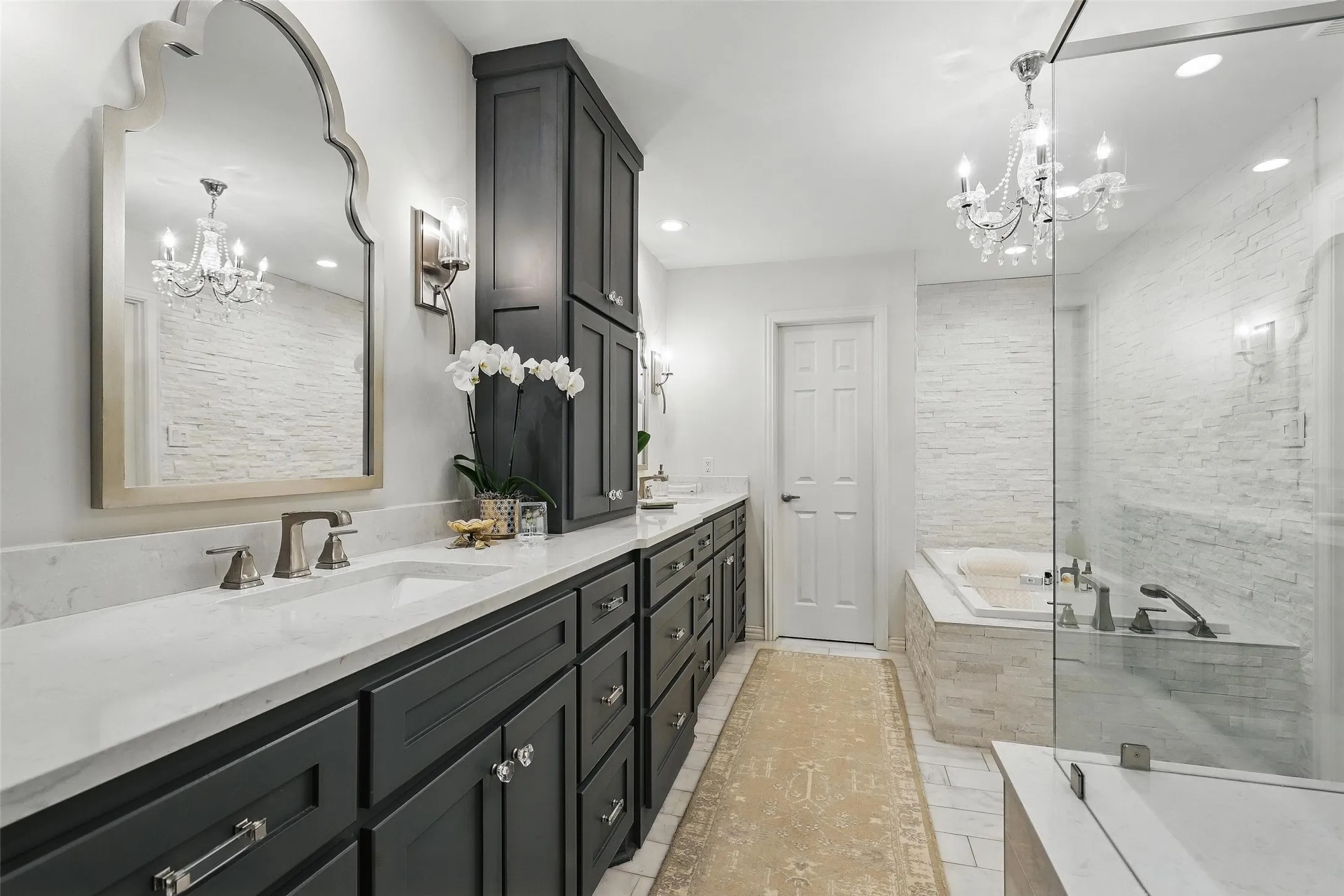Bathroom with a chandelier, double vanity, a bath, and recessed lighting