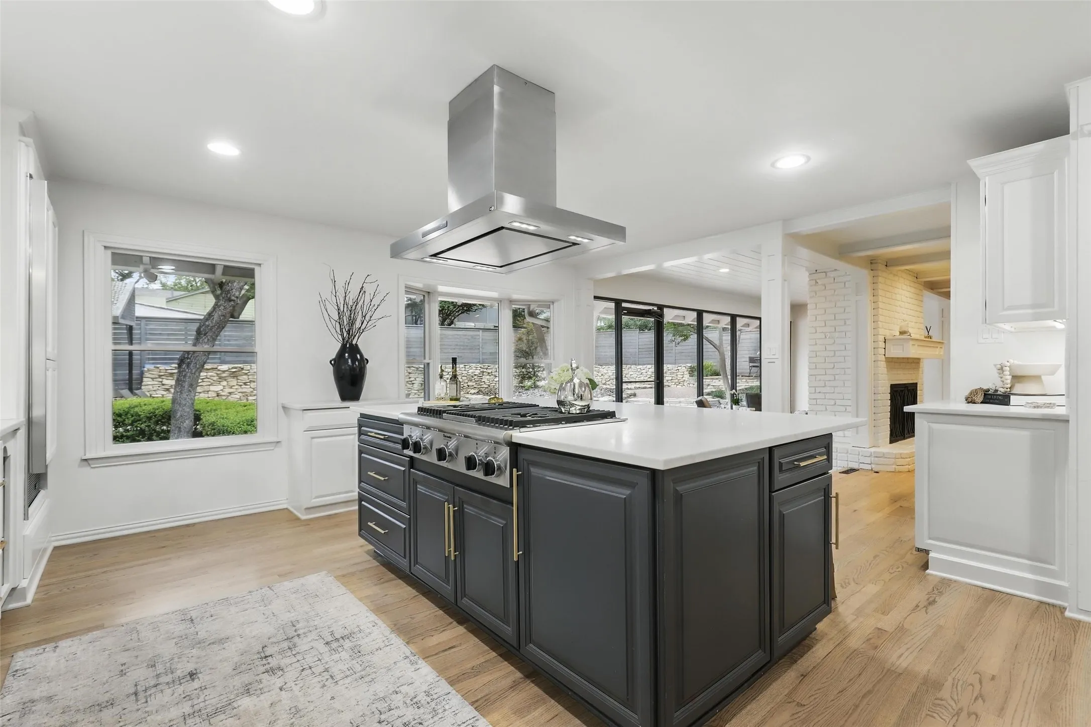 Kitchen with dark cabinetry, island exhaust hood, white cabinetry, and recessed lighting