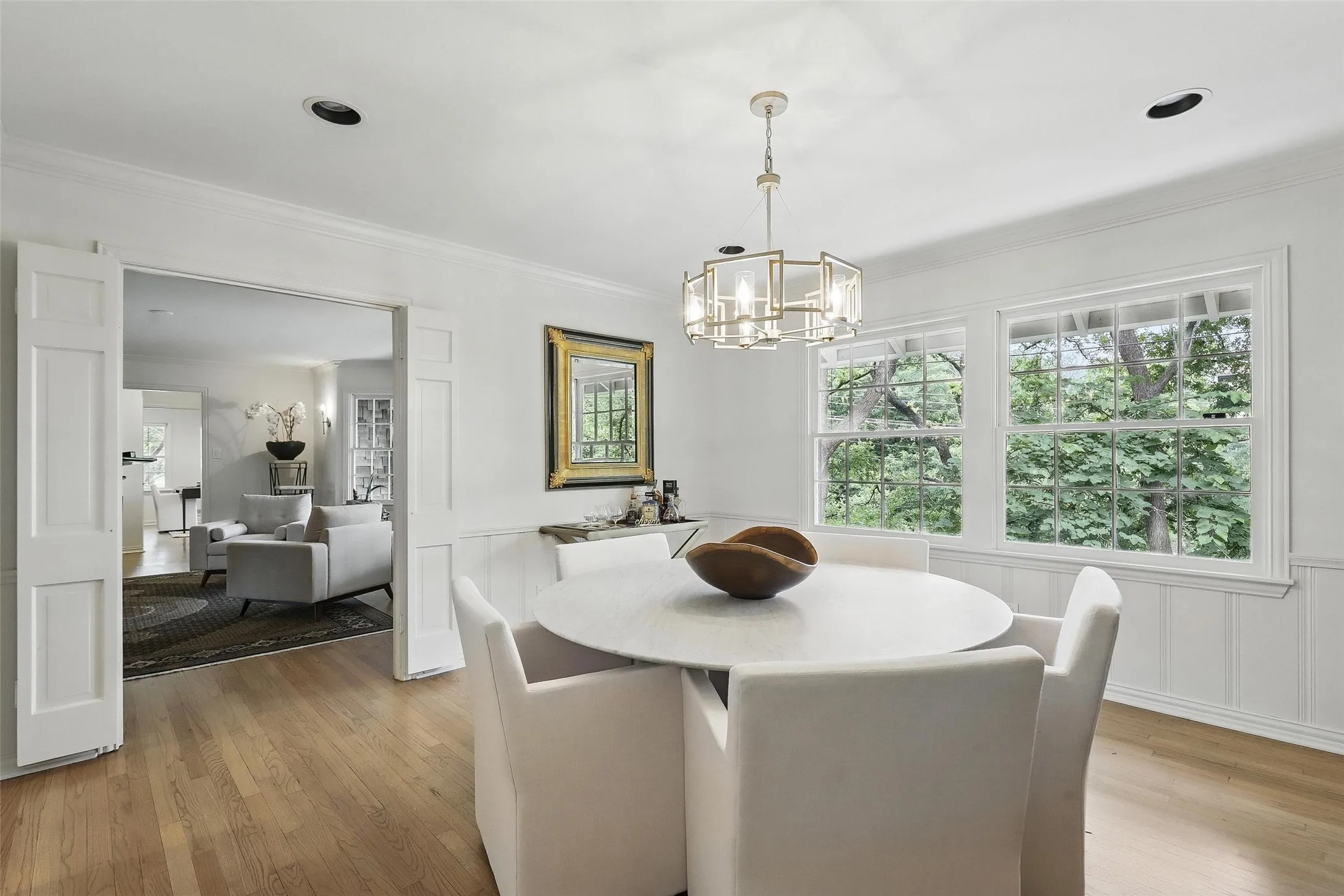 Dining space with wainscoting, a decorative wall, light wood-type flooring, ornamental molding, and a chandelier