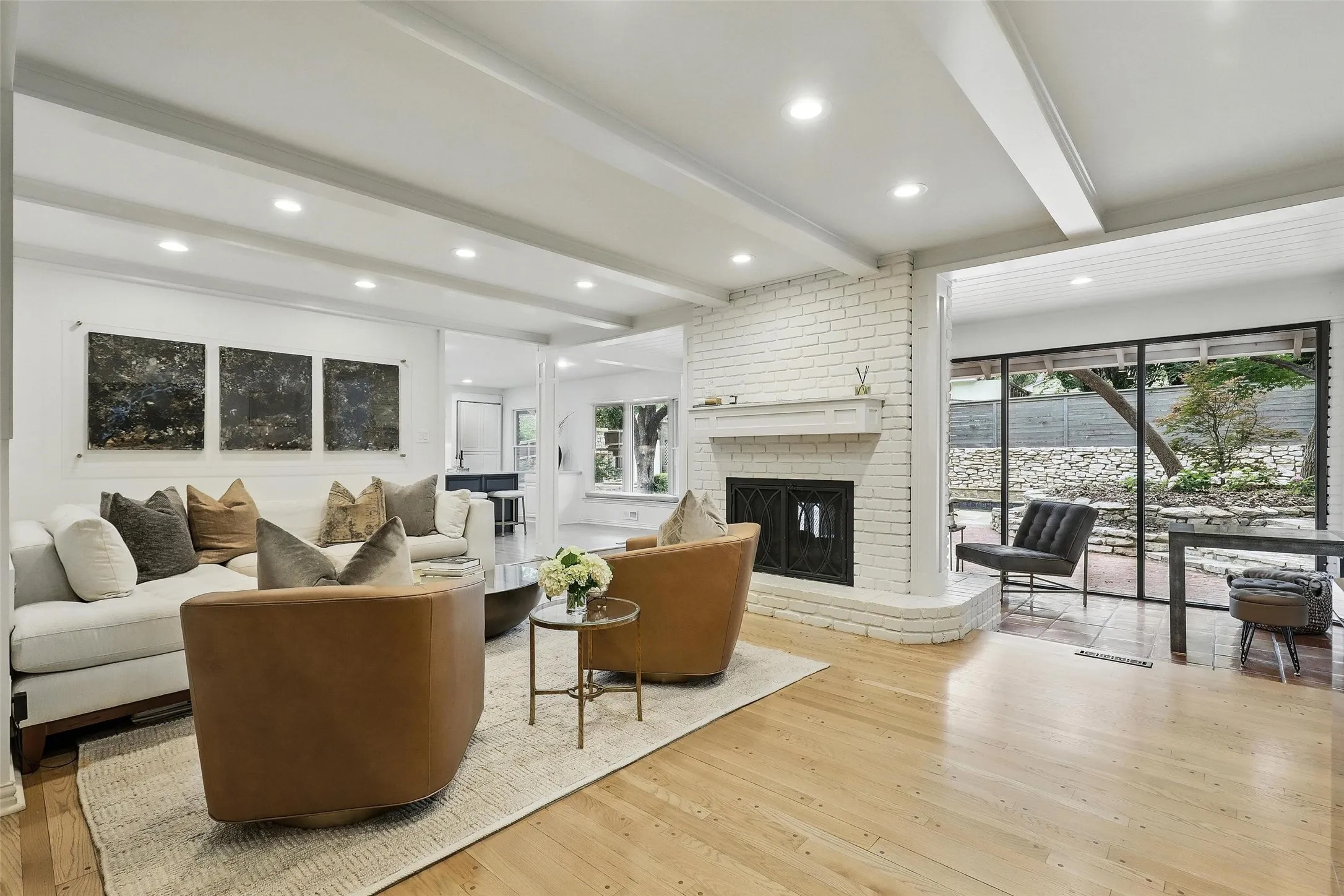 Living area featuring beam ceiling, a fireplace, light wood-type flooring, and recessed lighting
