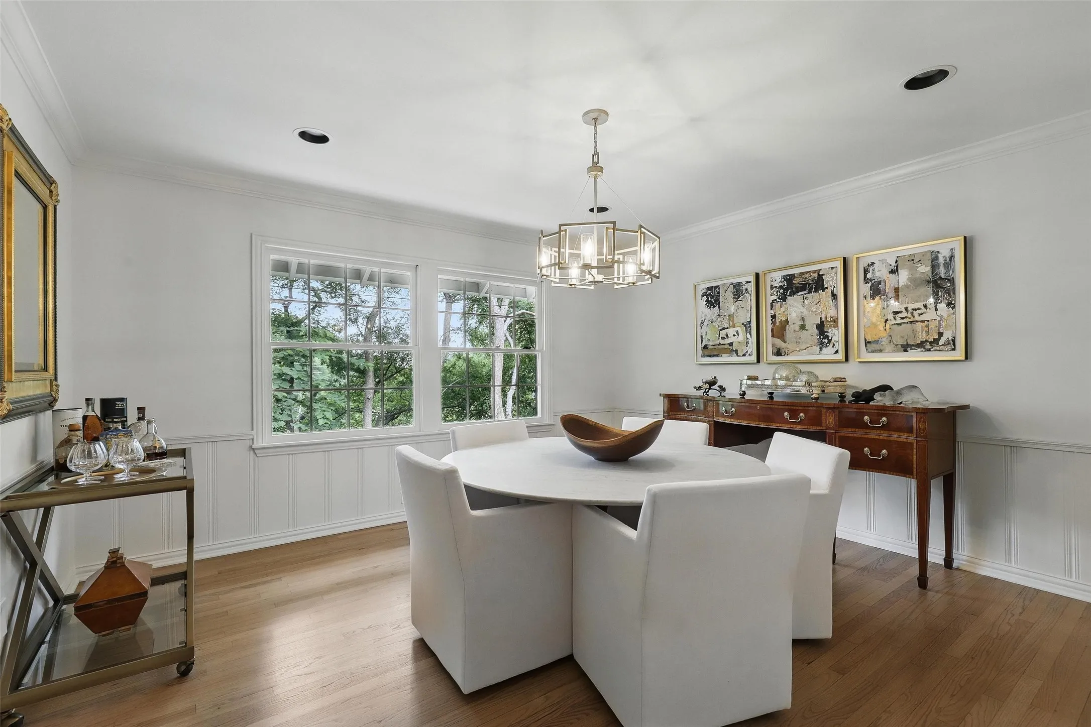 Dining room featuring a wainscoted wall, a decorative wall, light wood finished floors, ornamental molding, and a chandelier