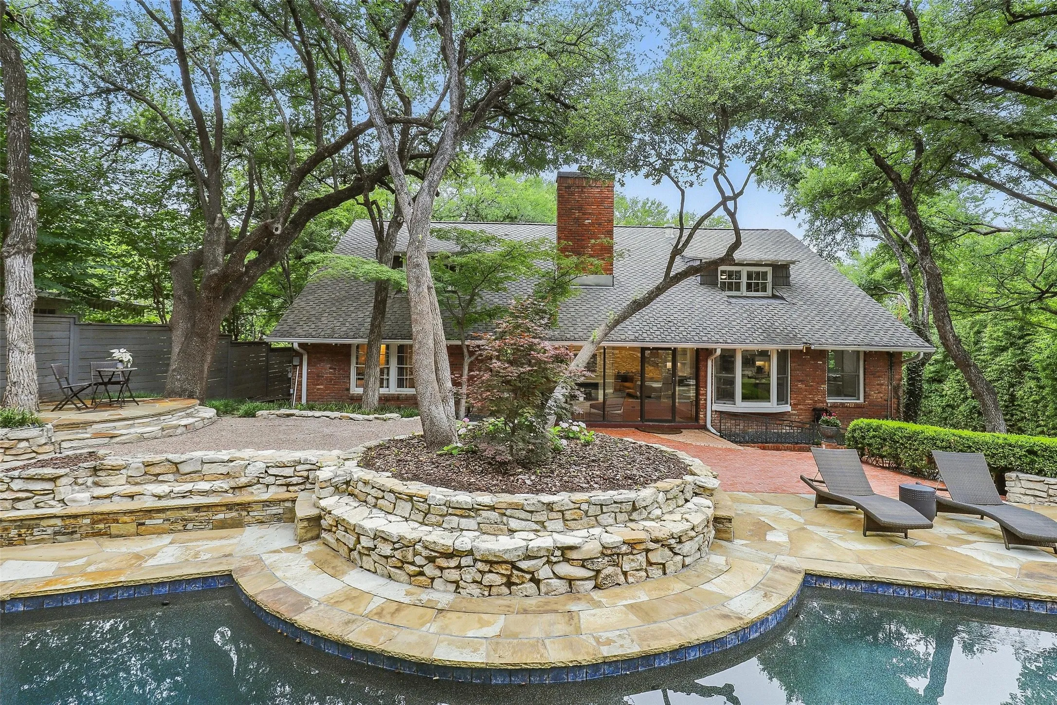Back of property with a patio area, an outdoor pool, brick siding, and a chimney
