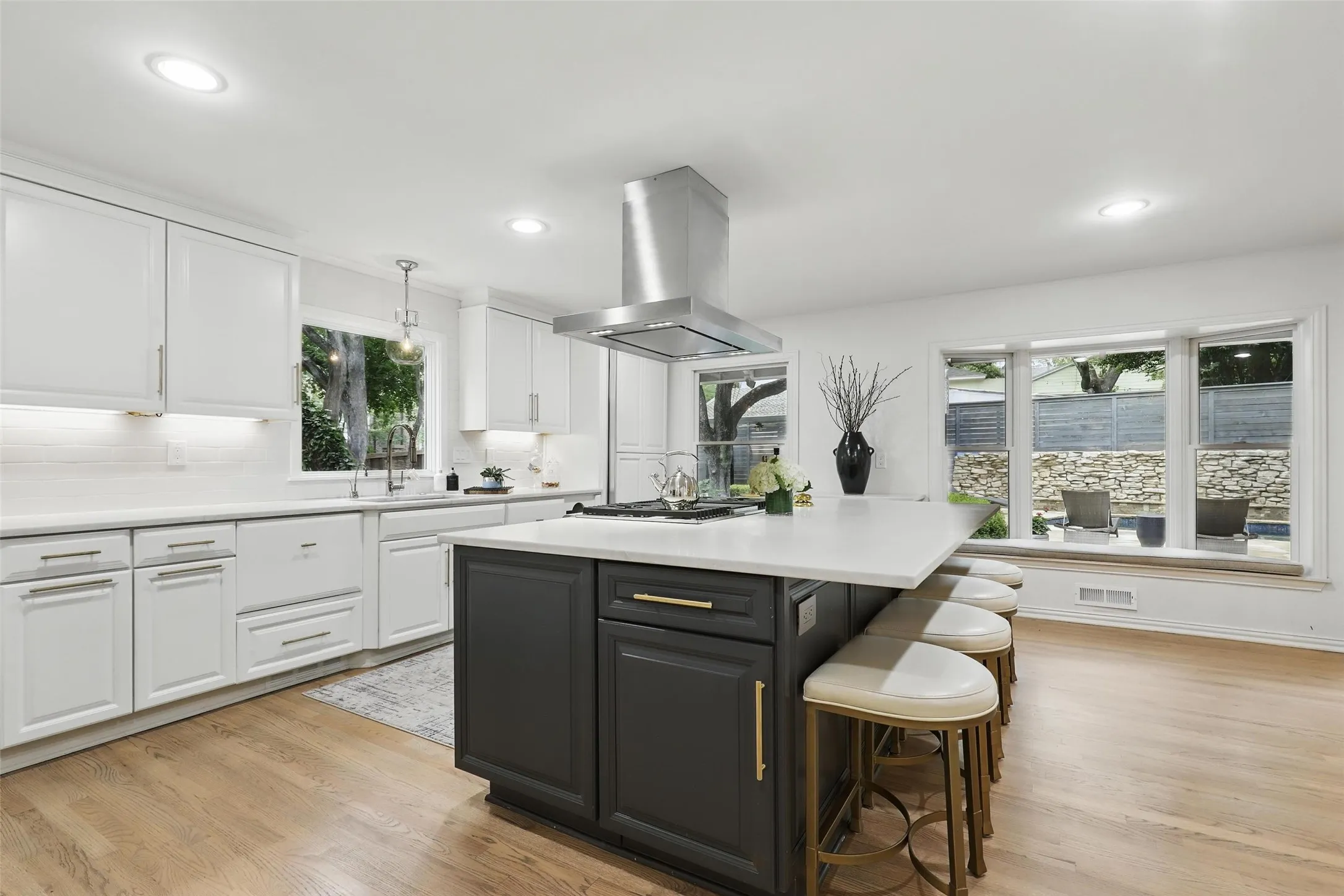 Kitchen with white cabinetry, light wood-type flooring, a breakfast bar, island range hood, and recessed lighting