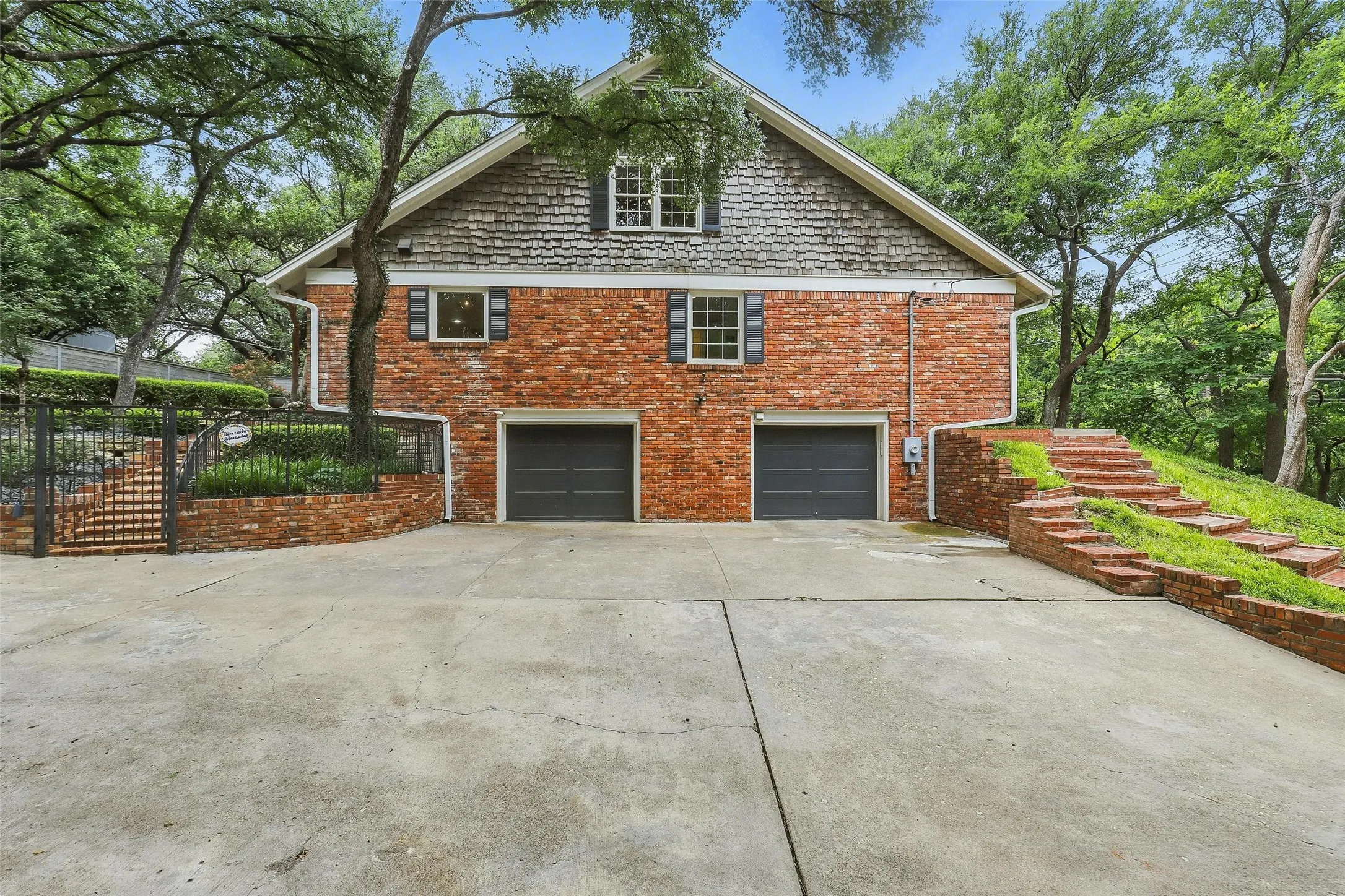 View of side of home with concrete driveway, brick siding, and an attached garage