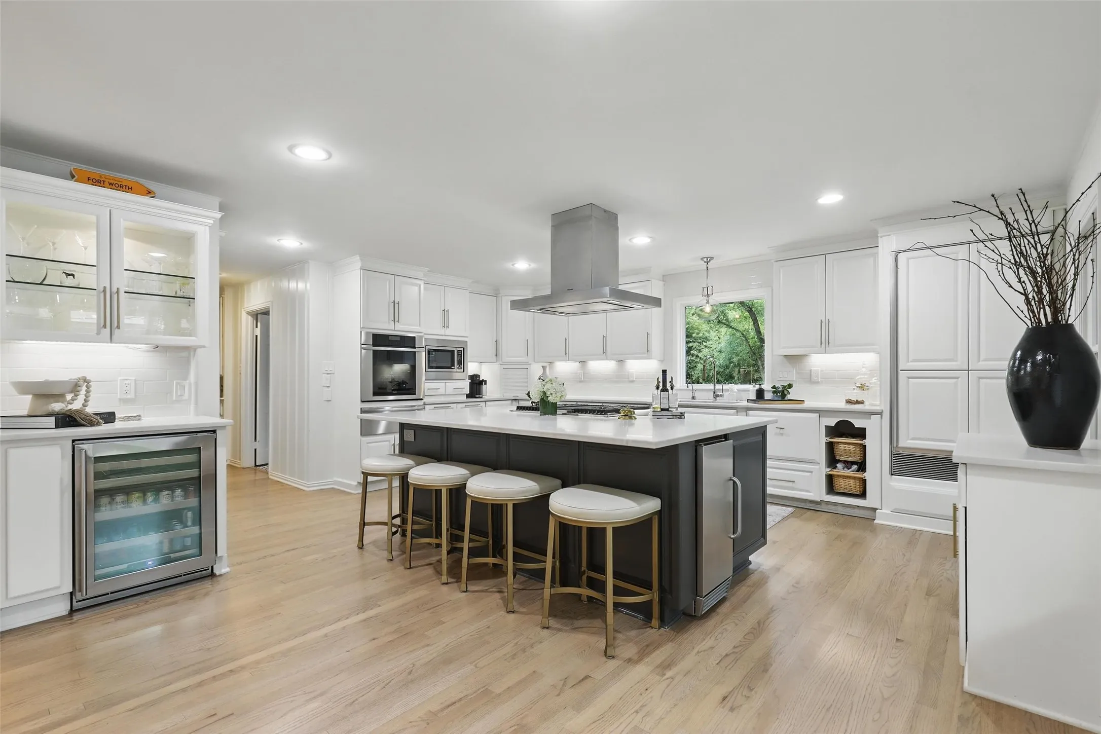 Kitchen with white cabinets, backsplash, glass insert cabinets, beverage cooler, and recessed lighting