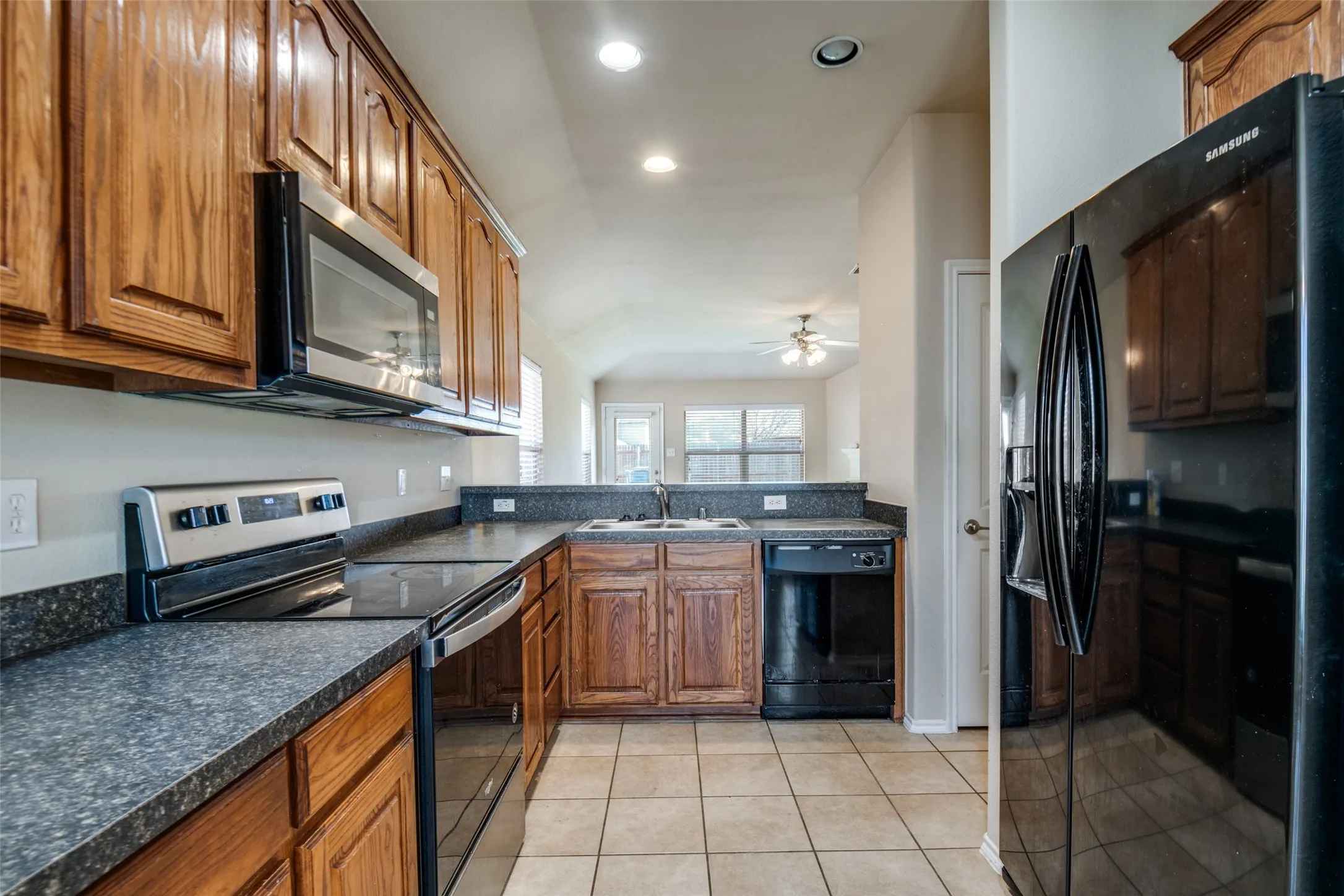 Kitchen featuring wood cabinetry, dark countertops, tile flooring, and stainless steel appliances