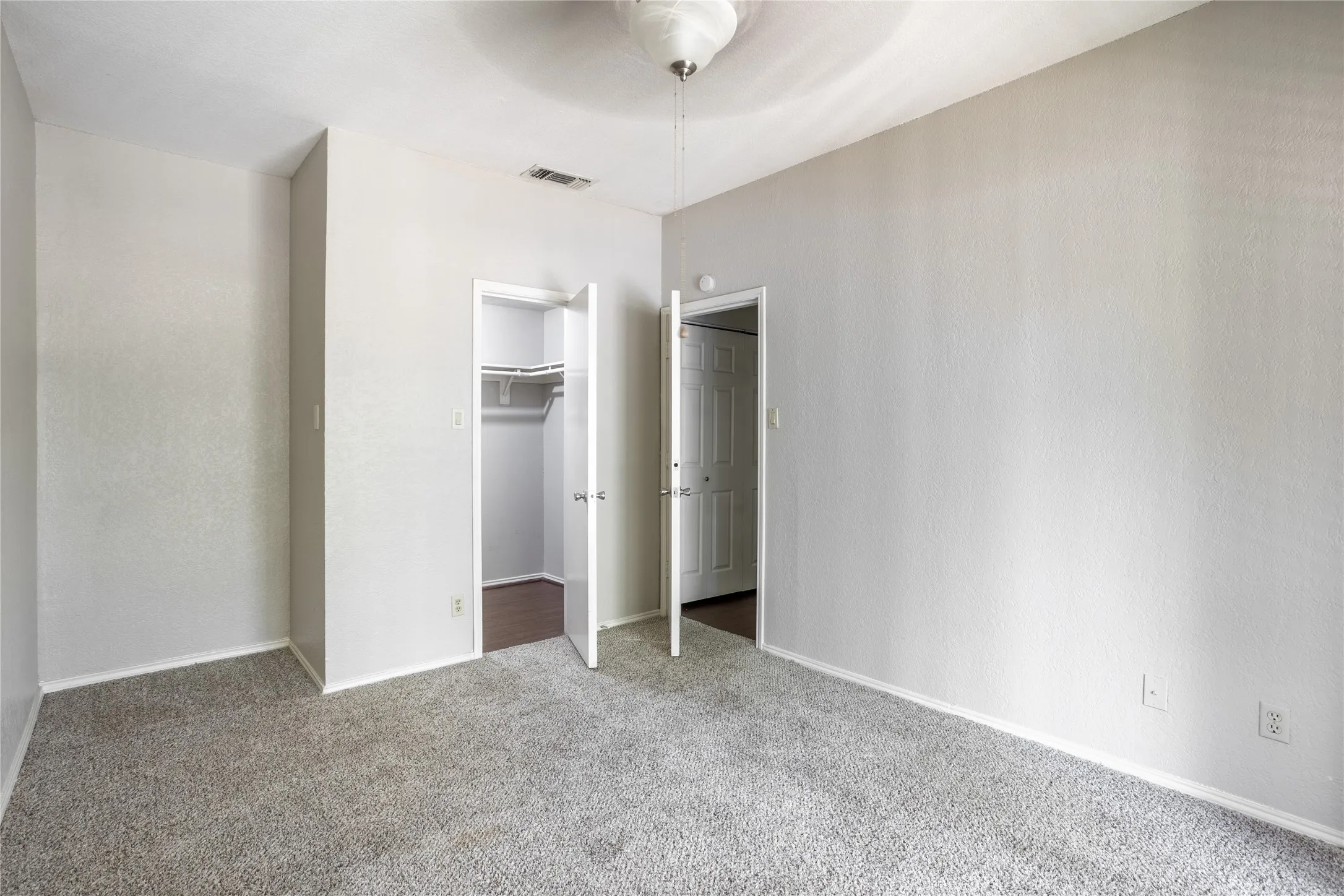 Unfurnished bedroom with a walk in closet, carpet flooring, and ceiling fan