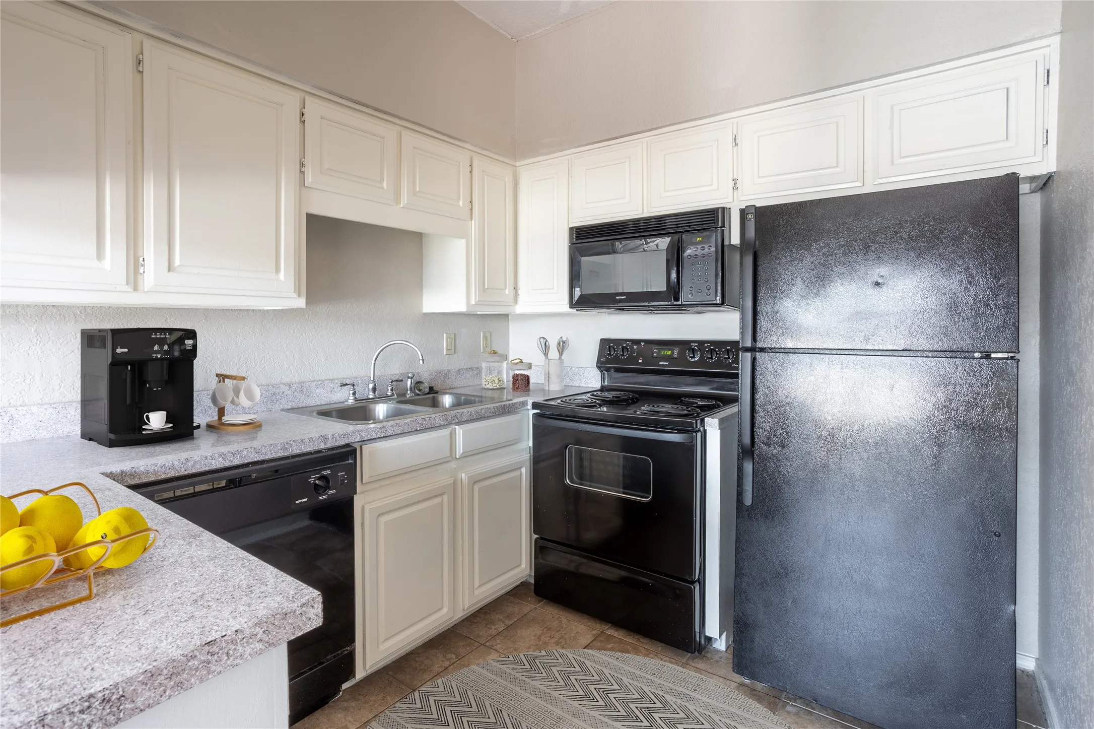Kitchen featuring black appliances, light countertops, white cabinets, and light tile patterned floors