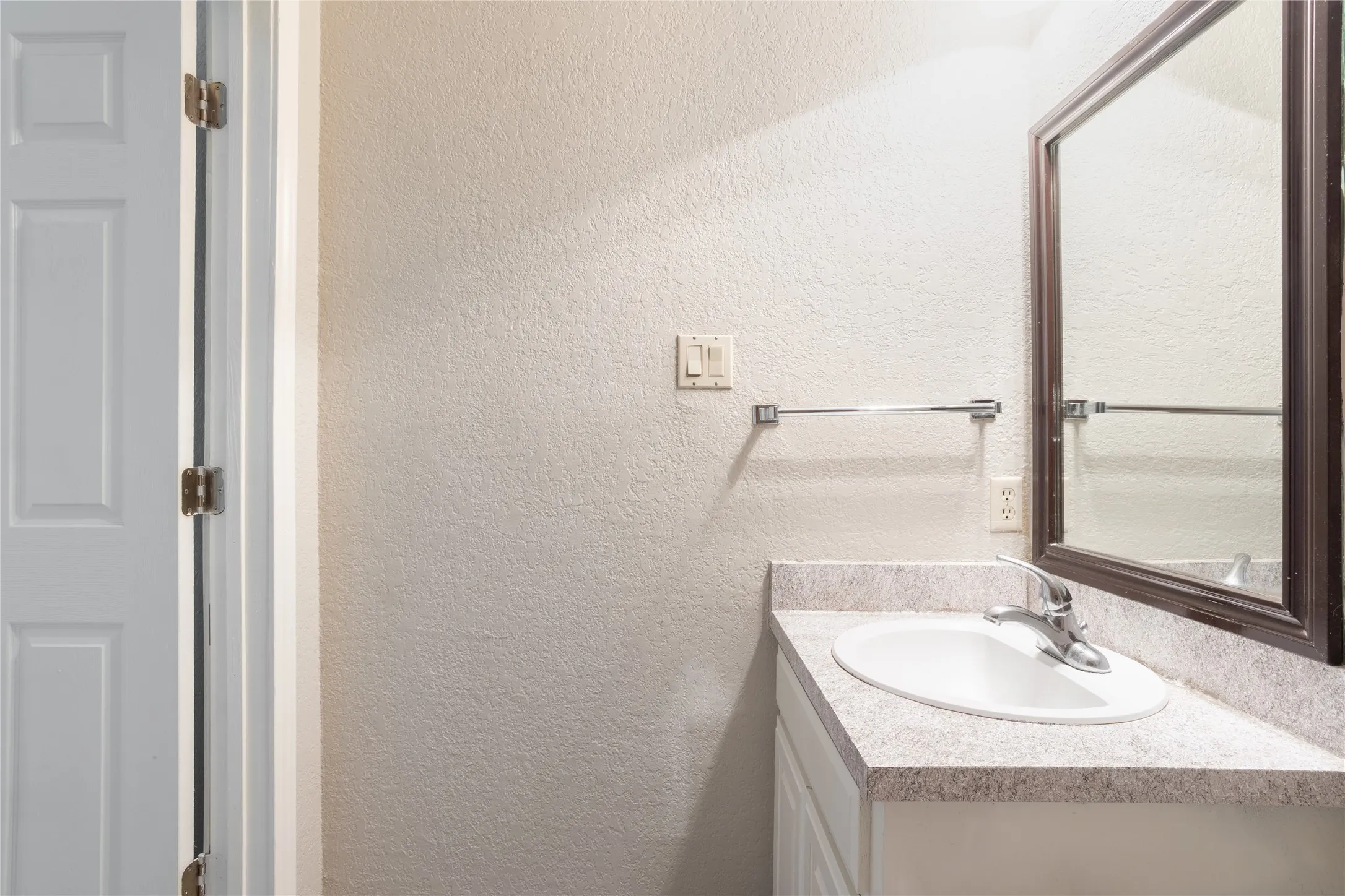 Bathroom with a textured wall and vanity