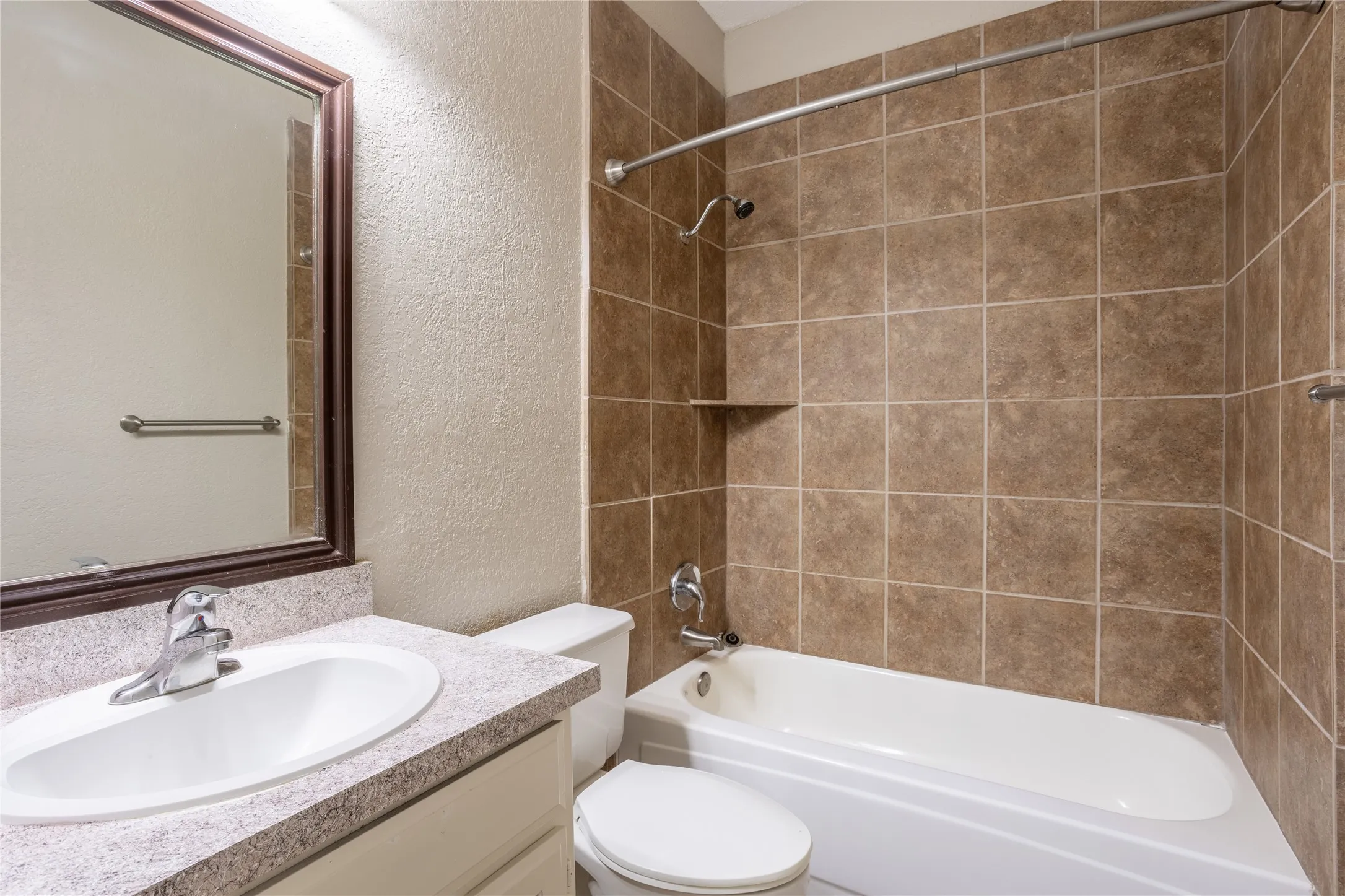 Full bathroom featuring a textured wall, vanity, and shower / washtub combination