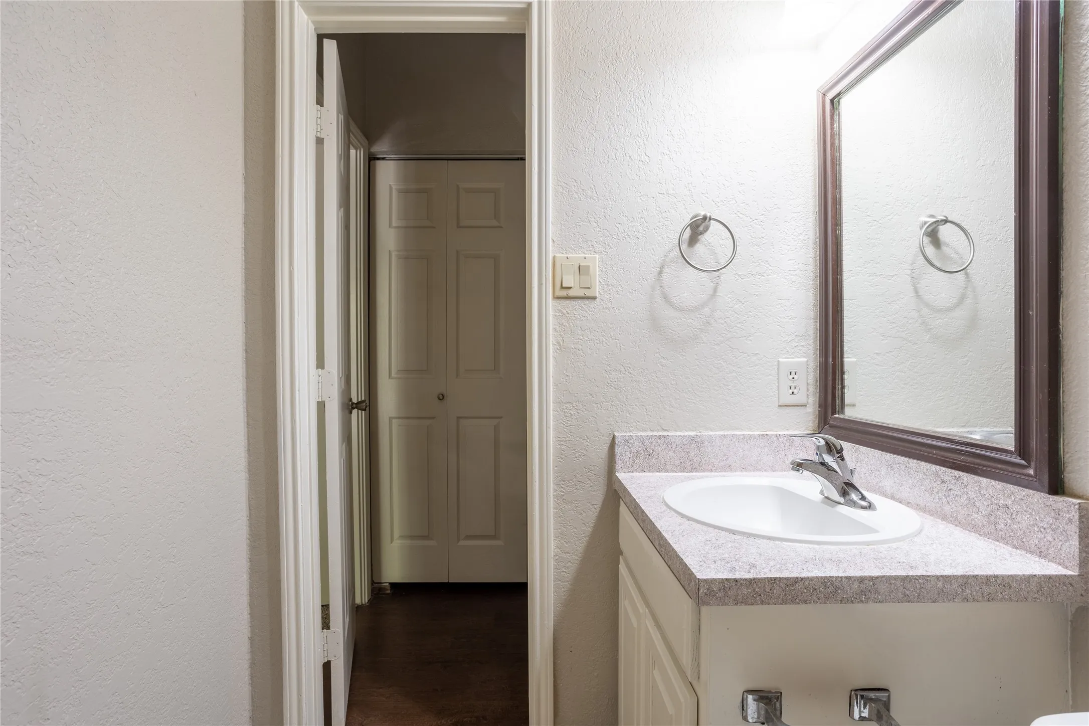 Half bathroom featuring a textured wall and vanity