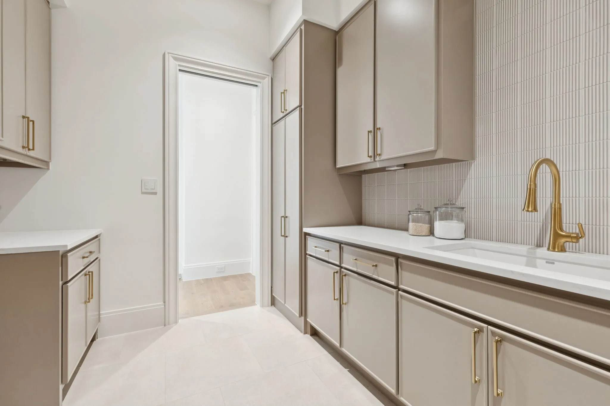 Kitchen with decorative backsplash, cream cabinets, light tile patterned floors, and light stone countertops