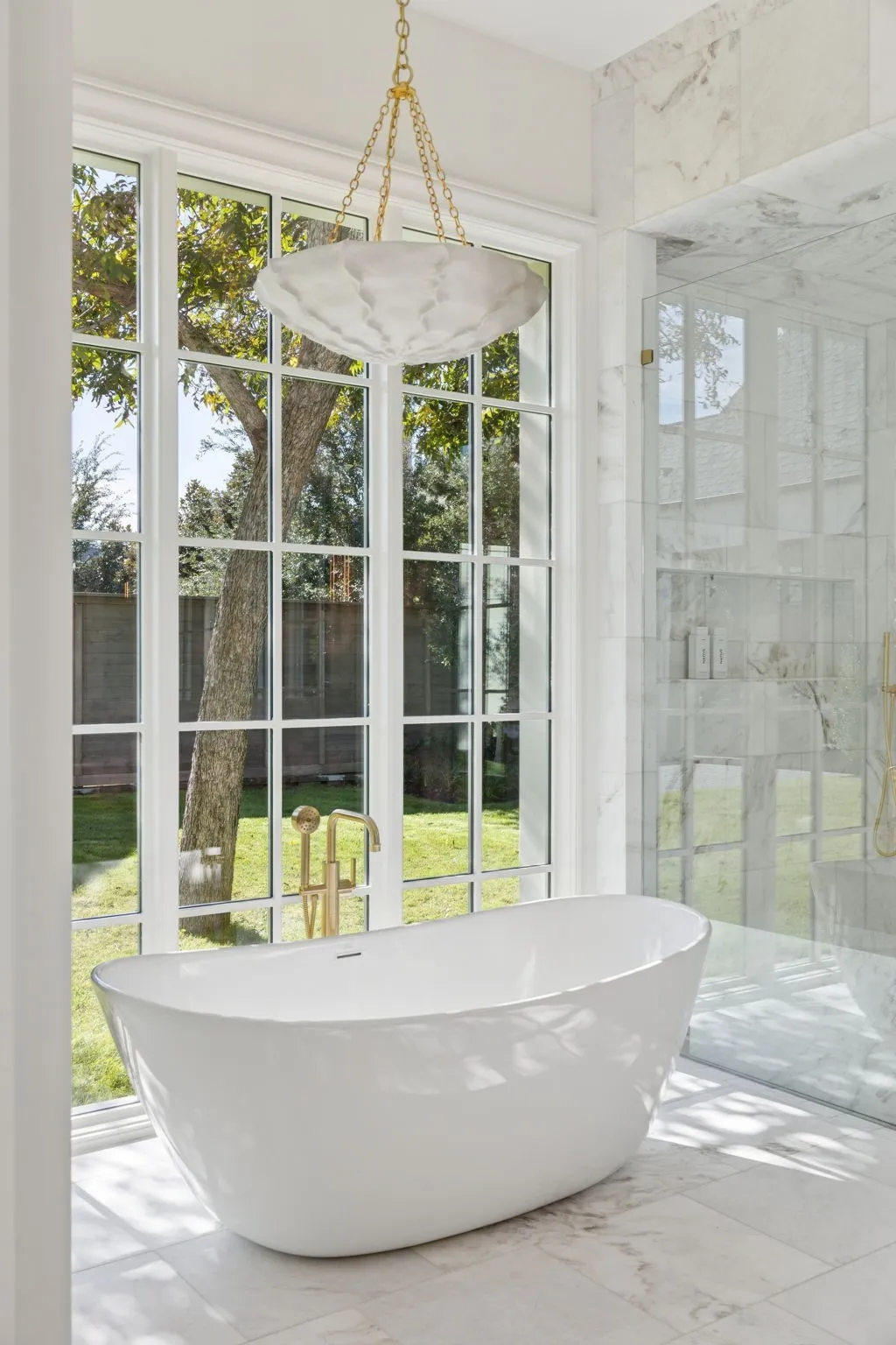 Bathroom with a freestanding bath, a marble finish shower, and marble tiled floors