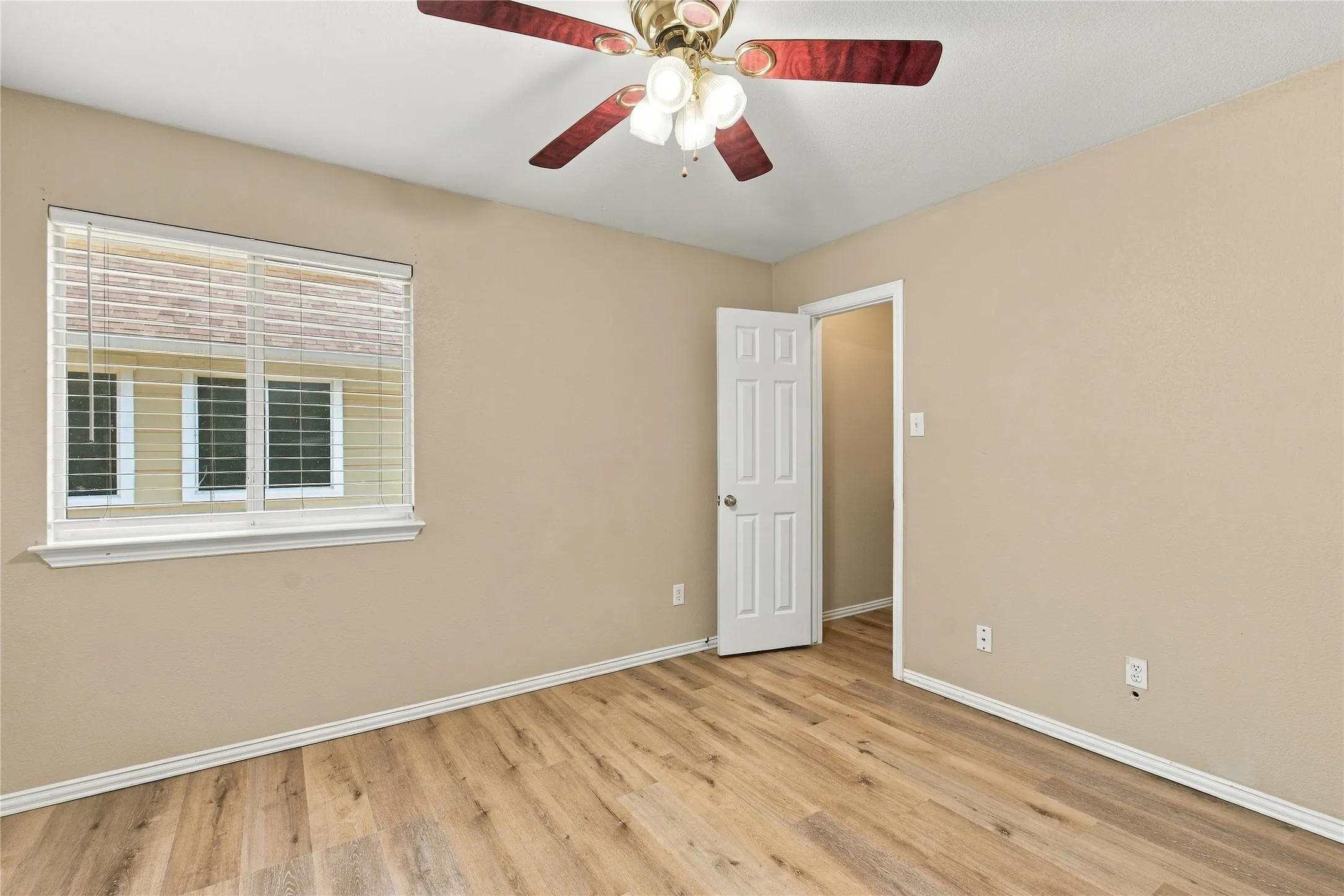 Neutral tone walls, wood-finish flooring, and a ceiling fan with integrated lighting