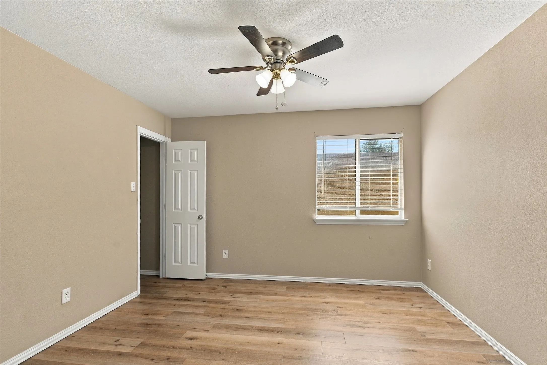 Wood-finish flooring, neutral wall tones, white trim, and a ceiling fan with integrated lighting