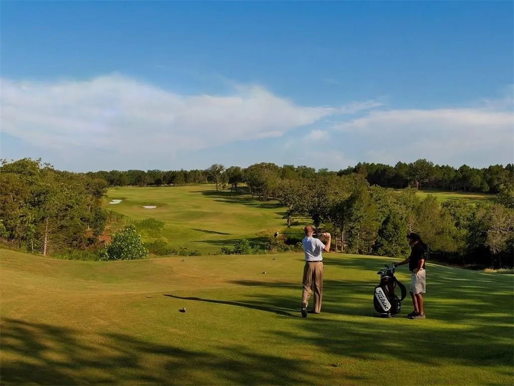 View of home's community with a lawn, golf course view, and view of wooded area