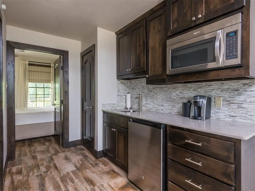 Kitchen with stainless steel appliances, dark brown cabinetry, backsplash, and light countertops