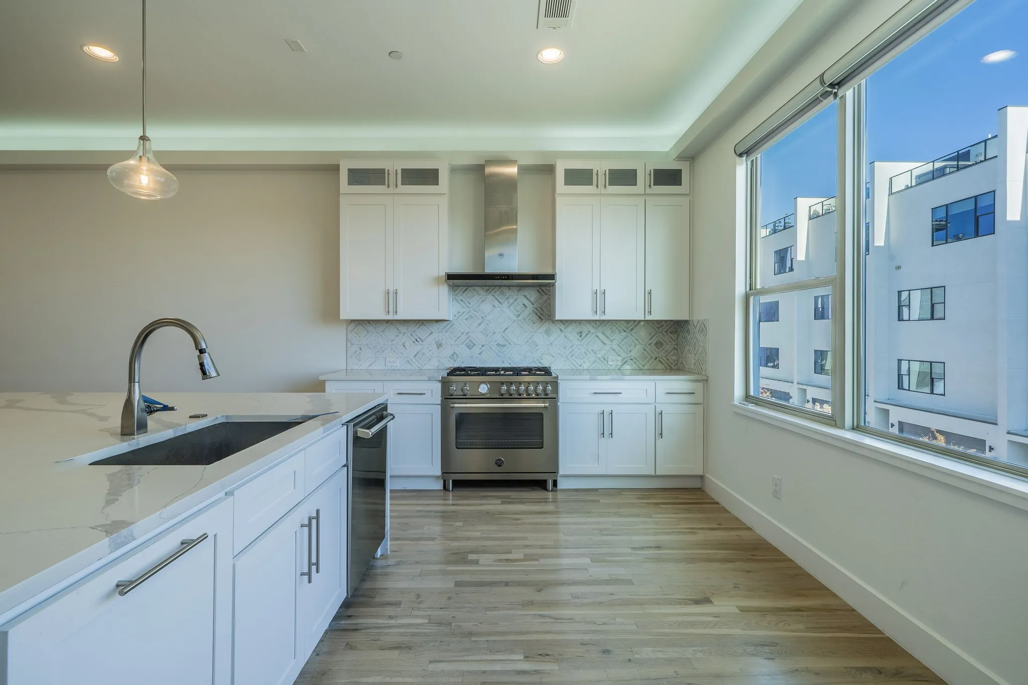 Kitchen featuring white cabinets, decorative light fixtures, light stone counters, stainless steel appliances, and recessed lighting