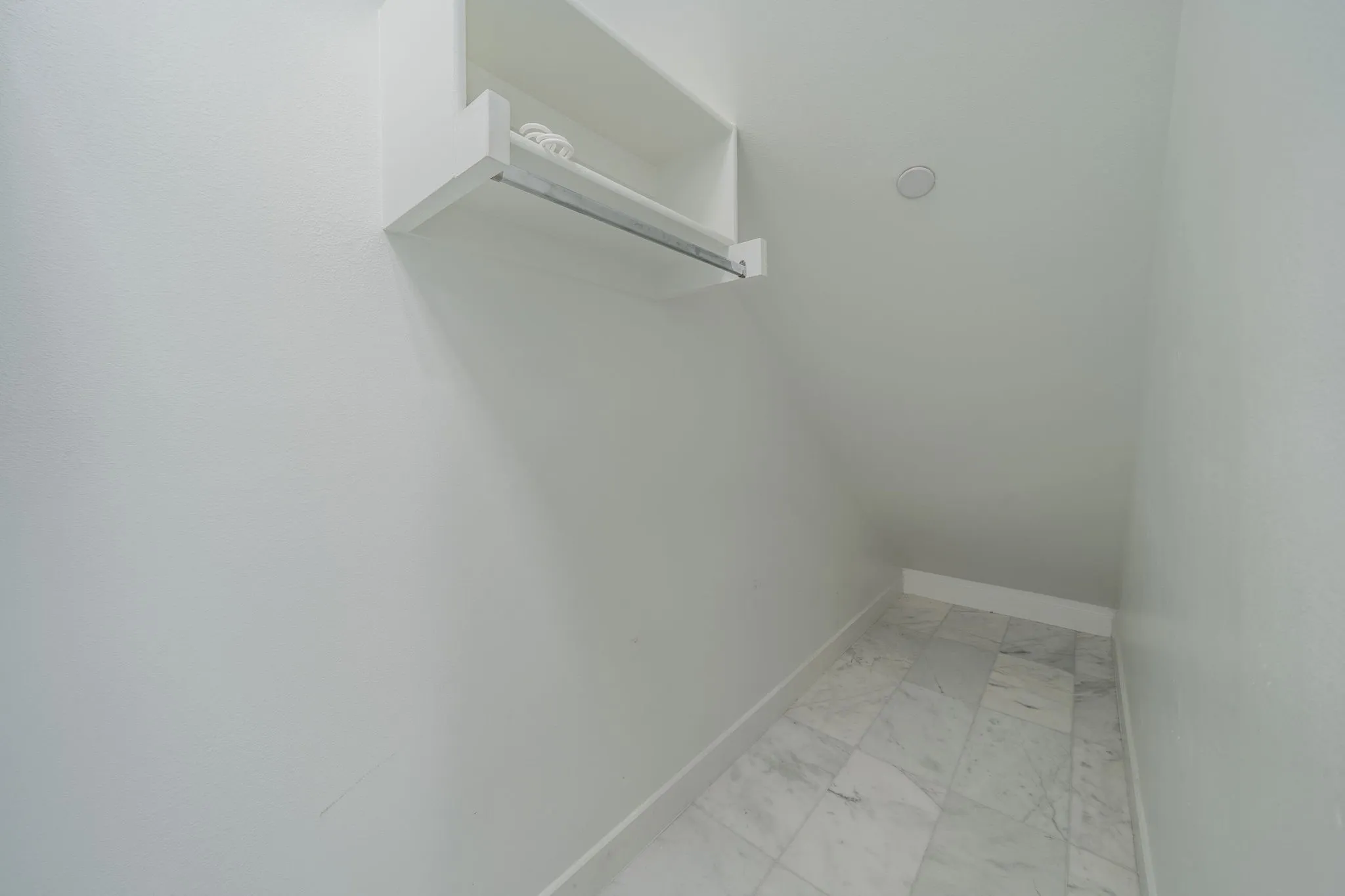 Spacious closet featuring light marble finish floors