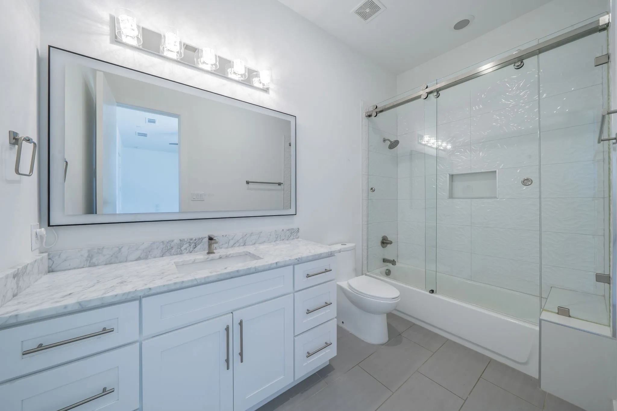 Full bath with vanity, bath / shower combo with glass door, and light tile patterned floors- 2nd level ensuite bath