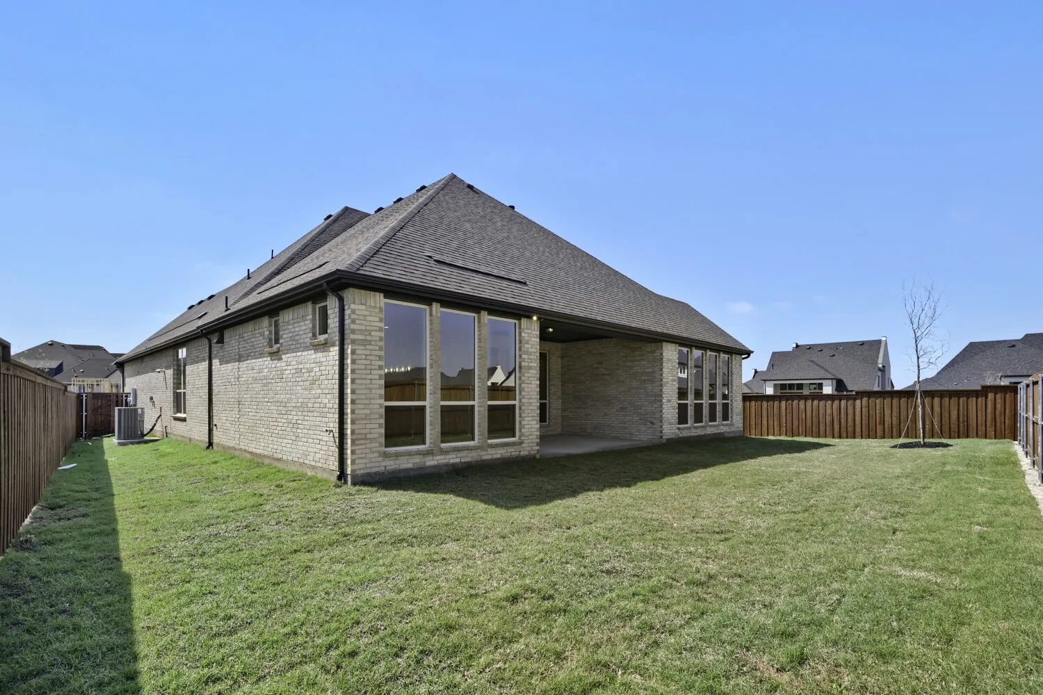 Back of property featuring brick siding, a fenced backyard, a patio area, and a shingled roof