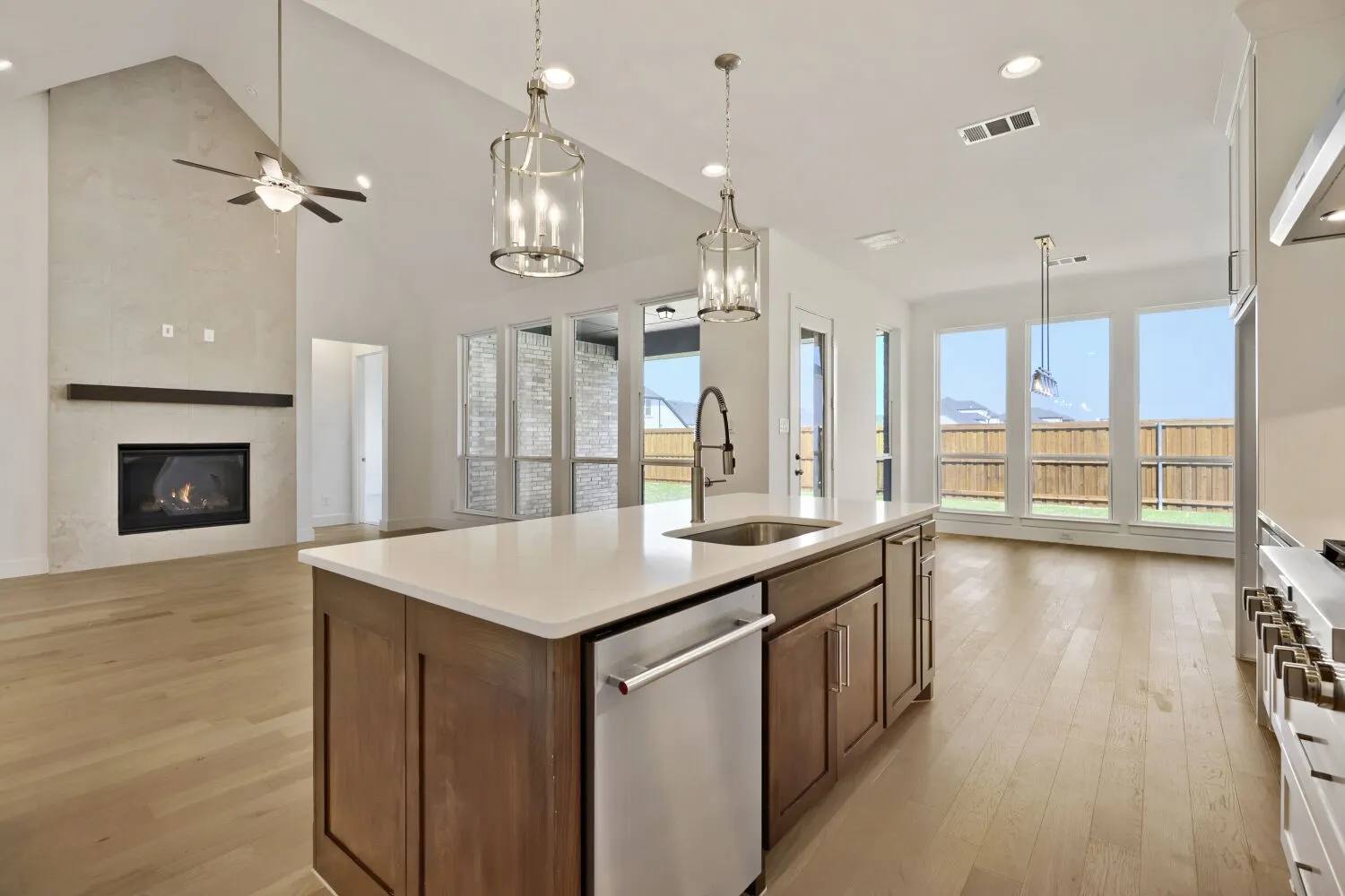 Kitchen with open floor plan, stainless steel appliances, light wood-style flooring, a tiled fireplace, and ceiling fan