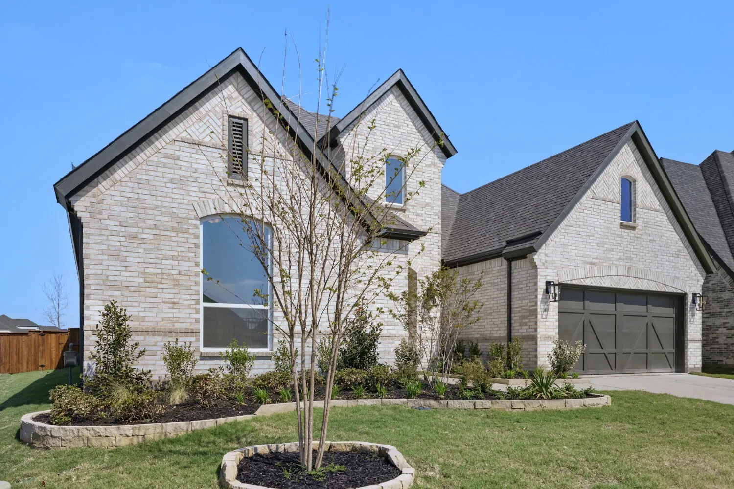 French country home with brick siding, a garage, and concrete driveway