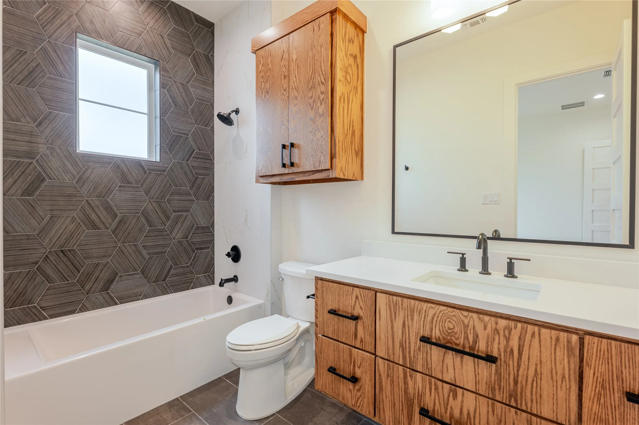 Bathroom with vanity, bathing tub / shower combination, and dark tile patterned floors