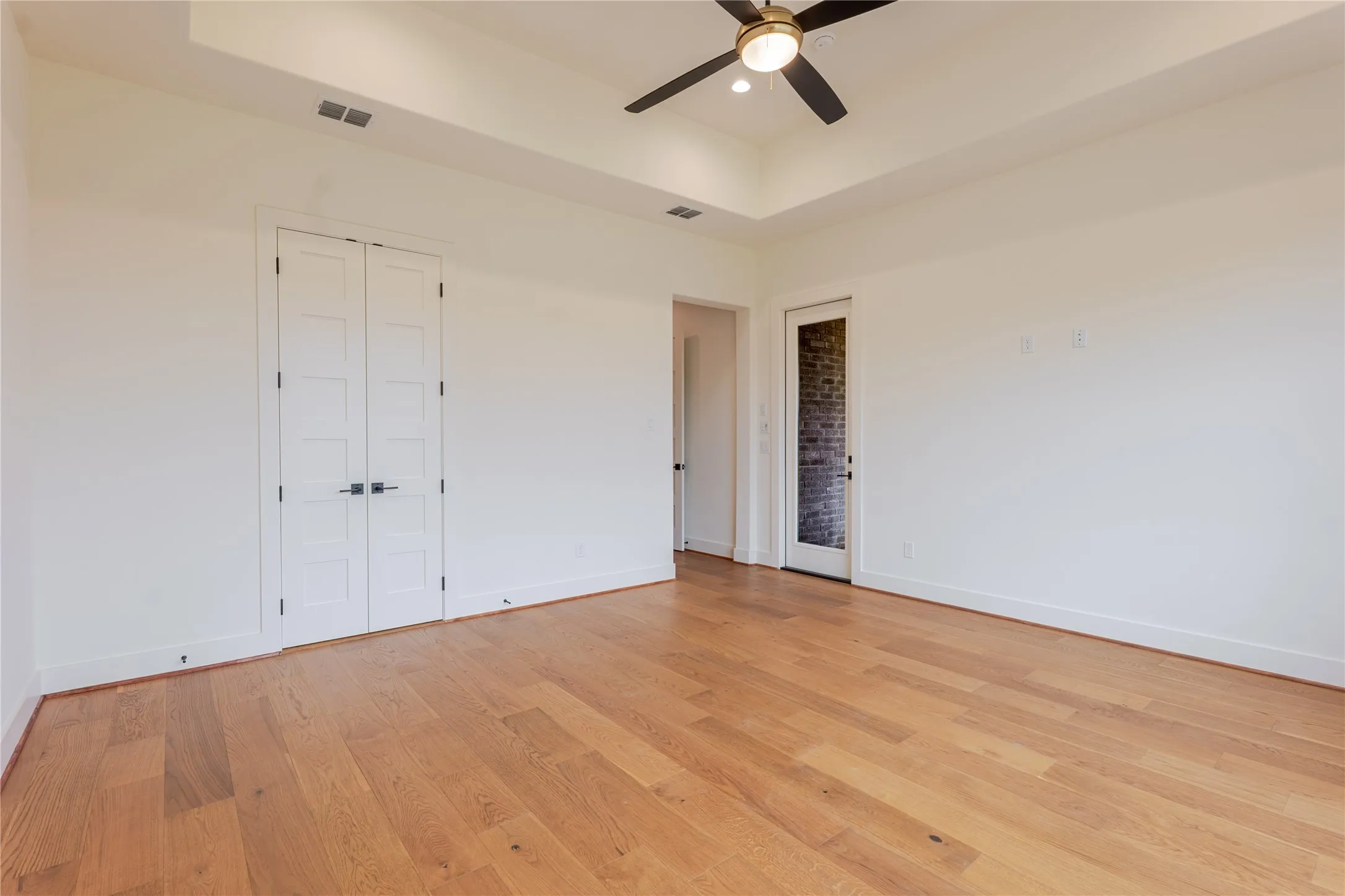 Unfurnished bedroom featuring a tray ceiling, a ceiling fan, light wood-style floors, recessed lighting, and a closet