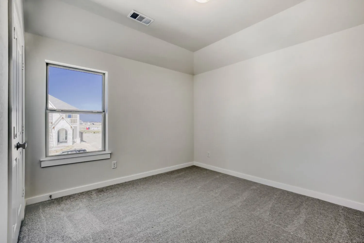 Empty room featuring light carpet and lofted ceiling