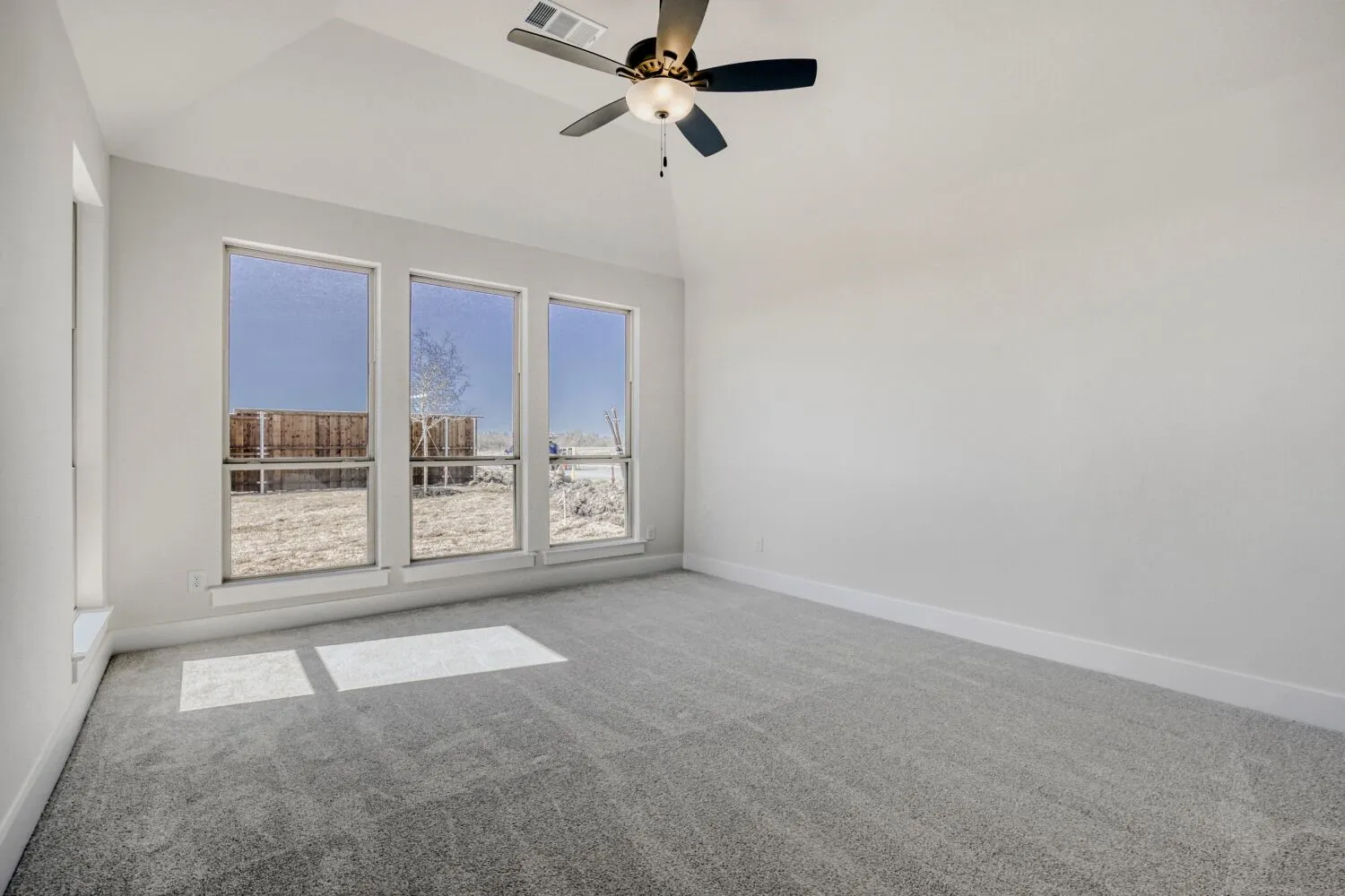 Spare room with light colored carpet, ceiling fan, and vaulted ceiling